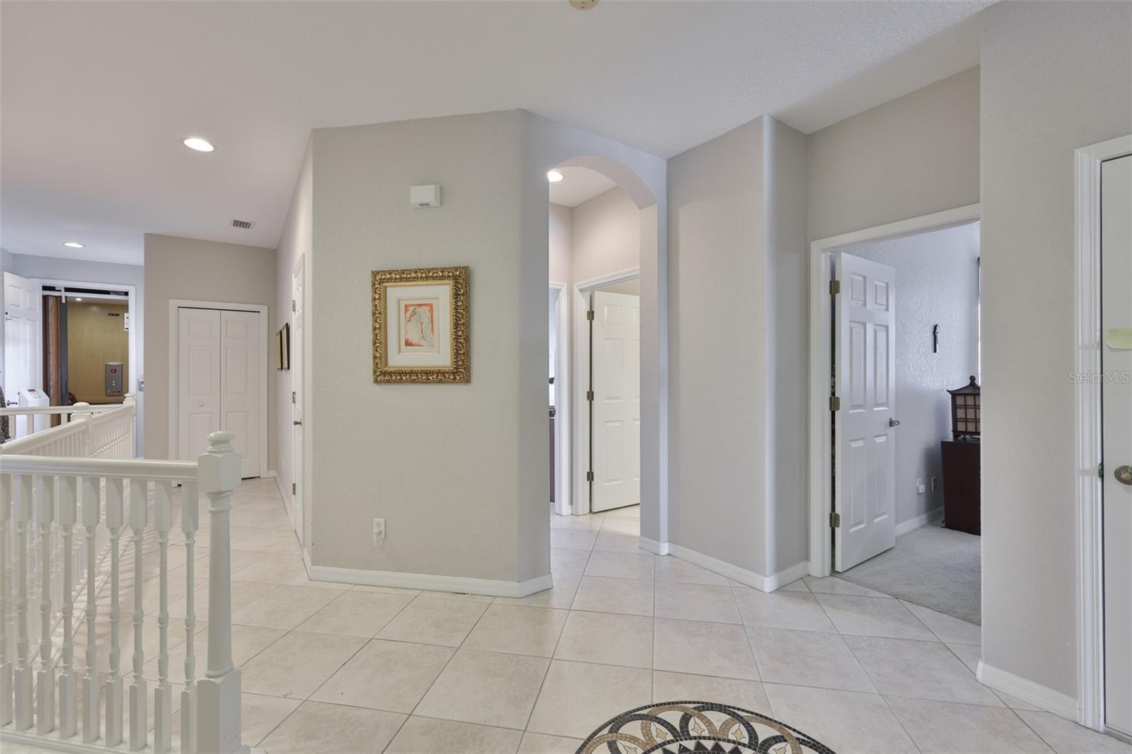 At the landing of the stairs, this area provides access to the den/office and two other bedrooms for maximum privacy for guests.  Notice the inlaid medallion in the floor and arched doorways.