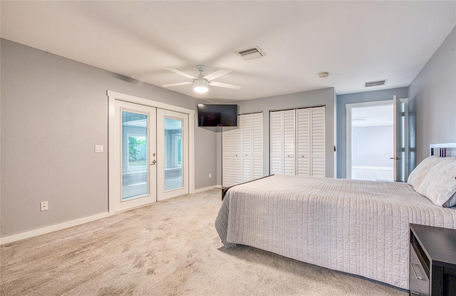 First Floor Primary Bedroom open to Living Area and French Doors closed to Pool Area