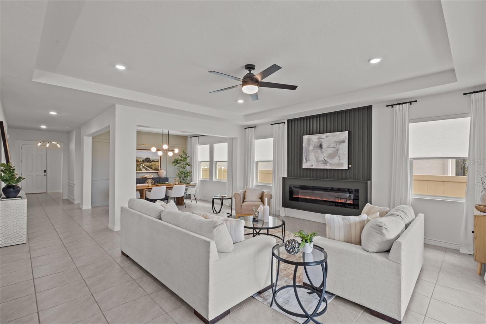 Light-filled great room with wood-look tile floors and a wall of stacking glass sliders that open completely to the covered lanai and pond views.