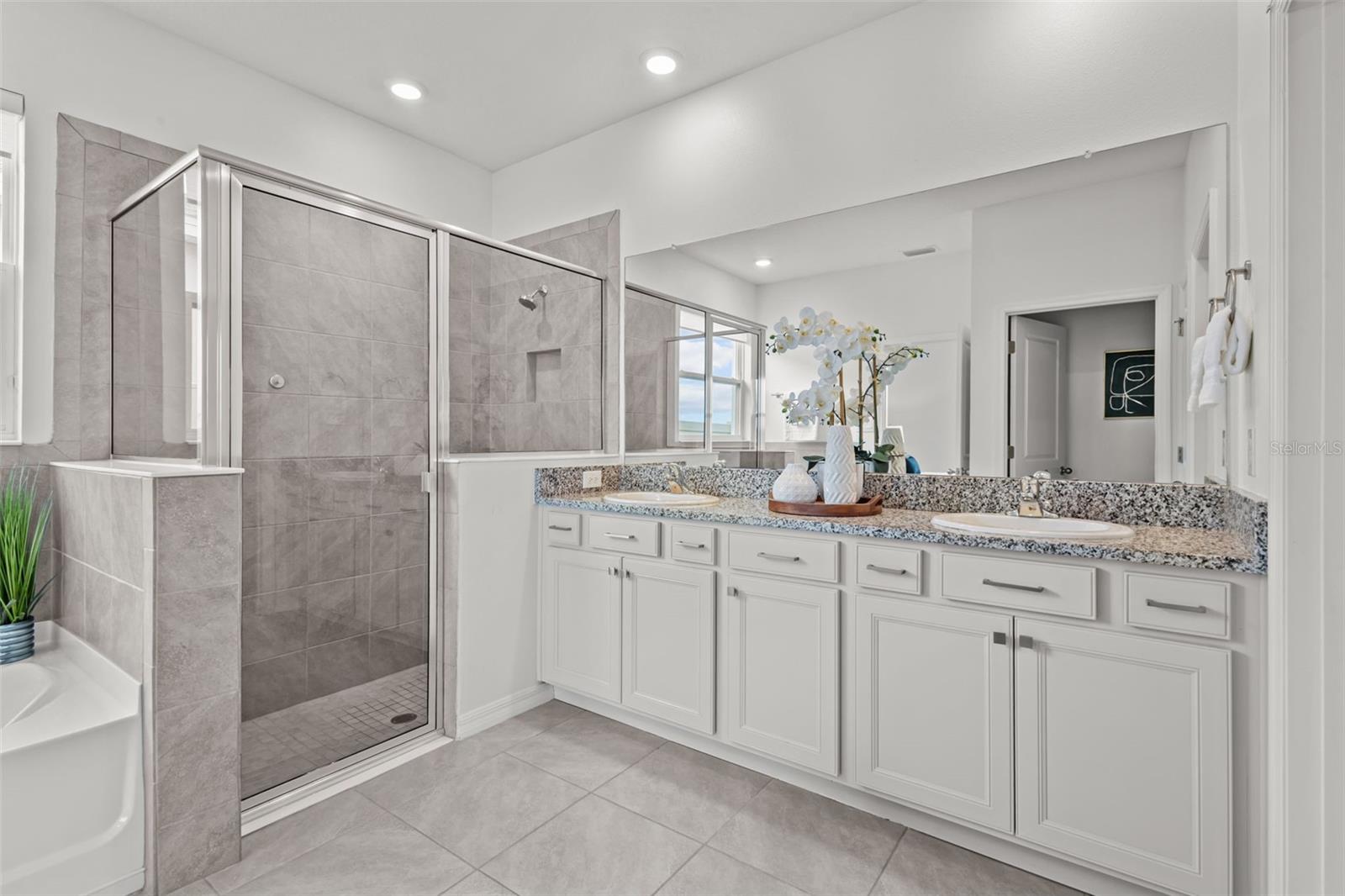 Spa-inspired primary bathroom with dual vanities, a large walk-in shower, and elegant finishes throughout.