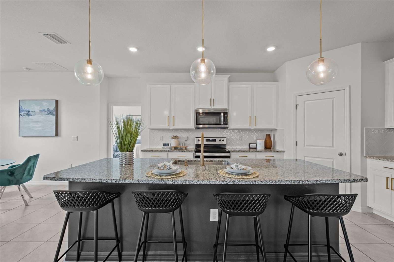 Chef’s kitchen designed for entertaining featuring a massive quartz island, gas cooktop, built-in ovens, designer backsplash, and abundant cabinetry.