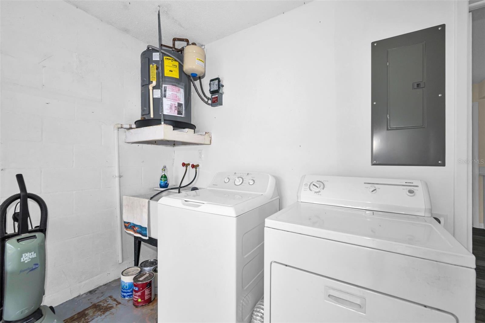 Laundry in garage with newer washer dryer and water heater