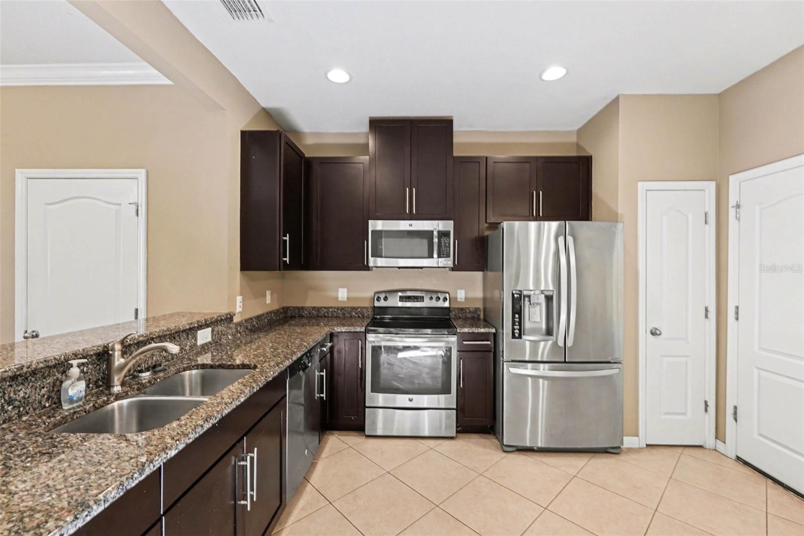 Modern kitchen featuring stone counters, a breakfast bar, and a full suite of included appliances.