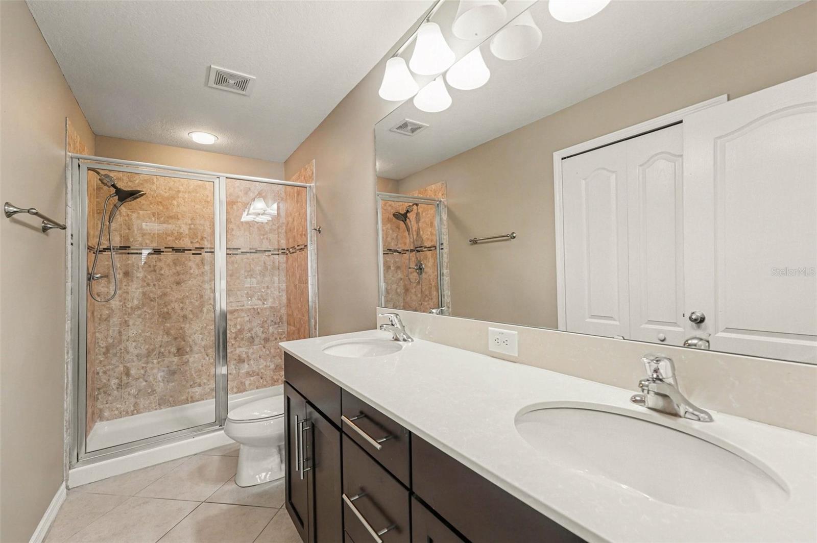 En-suite primary bath featuring dual sinks and a large walk-in shower