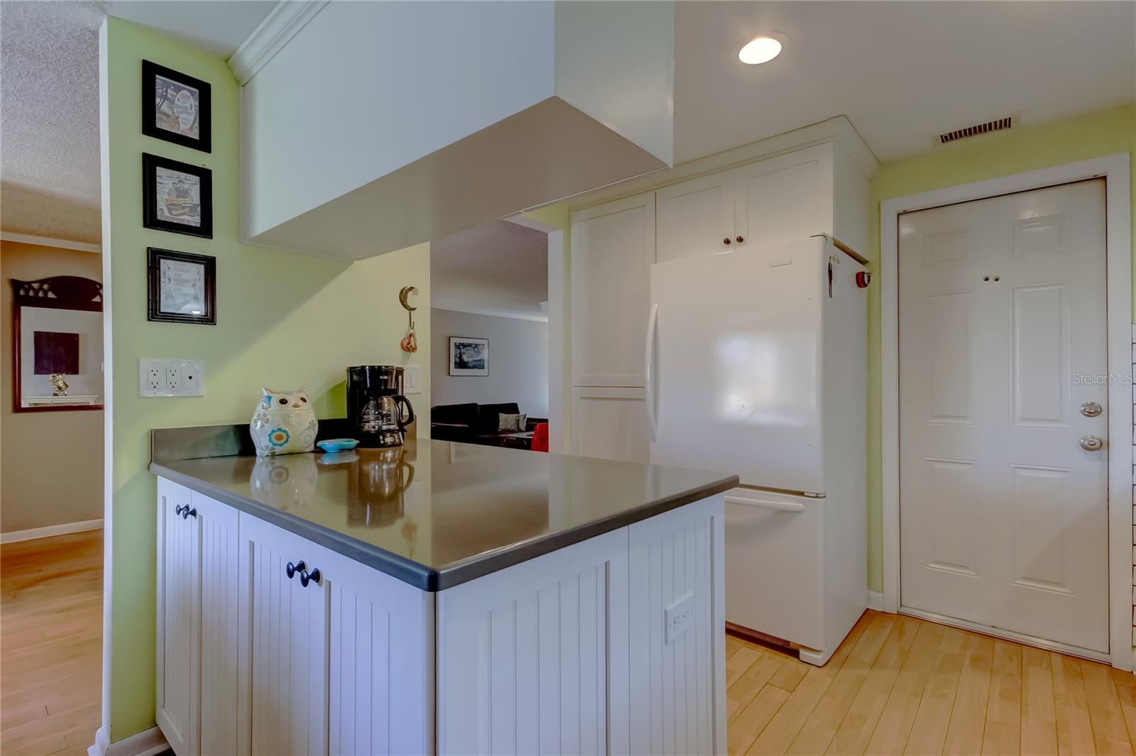Kitchen peninsula Corian countertops and overhead cabinetry