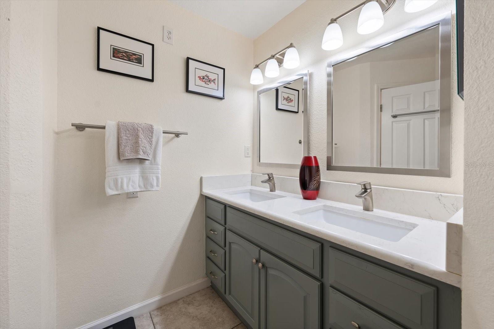 Primary bath area is tastefully updated with dual sinks and cabinetry.