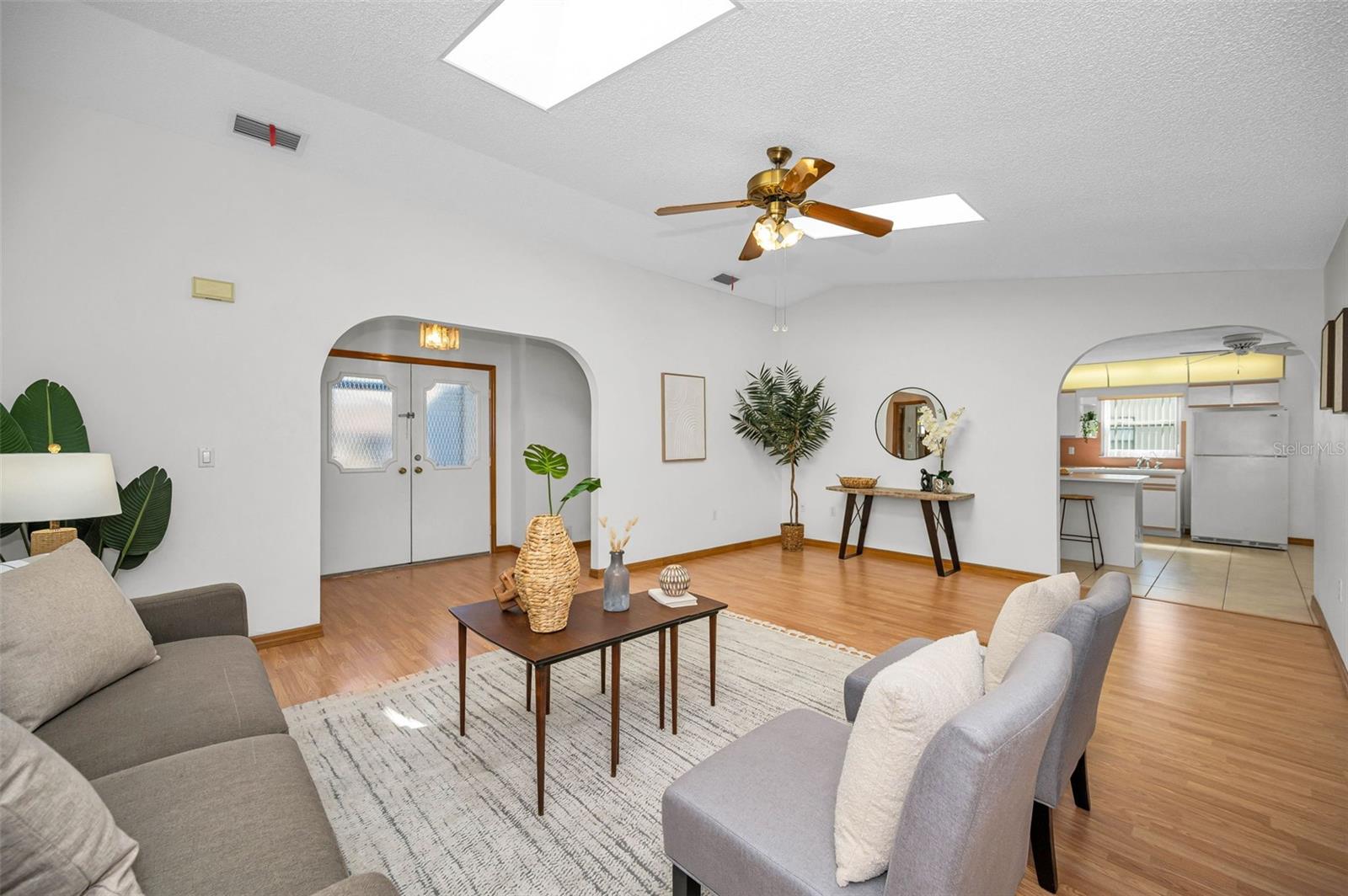 Walking into the Front Door, you'll immediately notice this is an extra-large, bright living room! It features two skylights and a vaulted ceiling. The room is connected to the kitchen, dining room, and Florida room, creating a spacious and open living area.