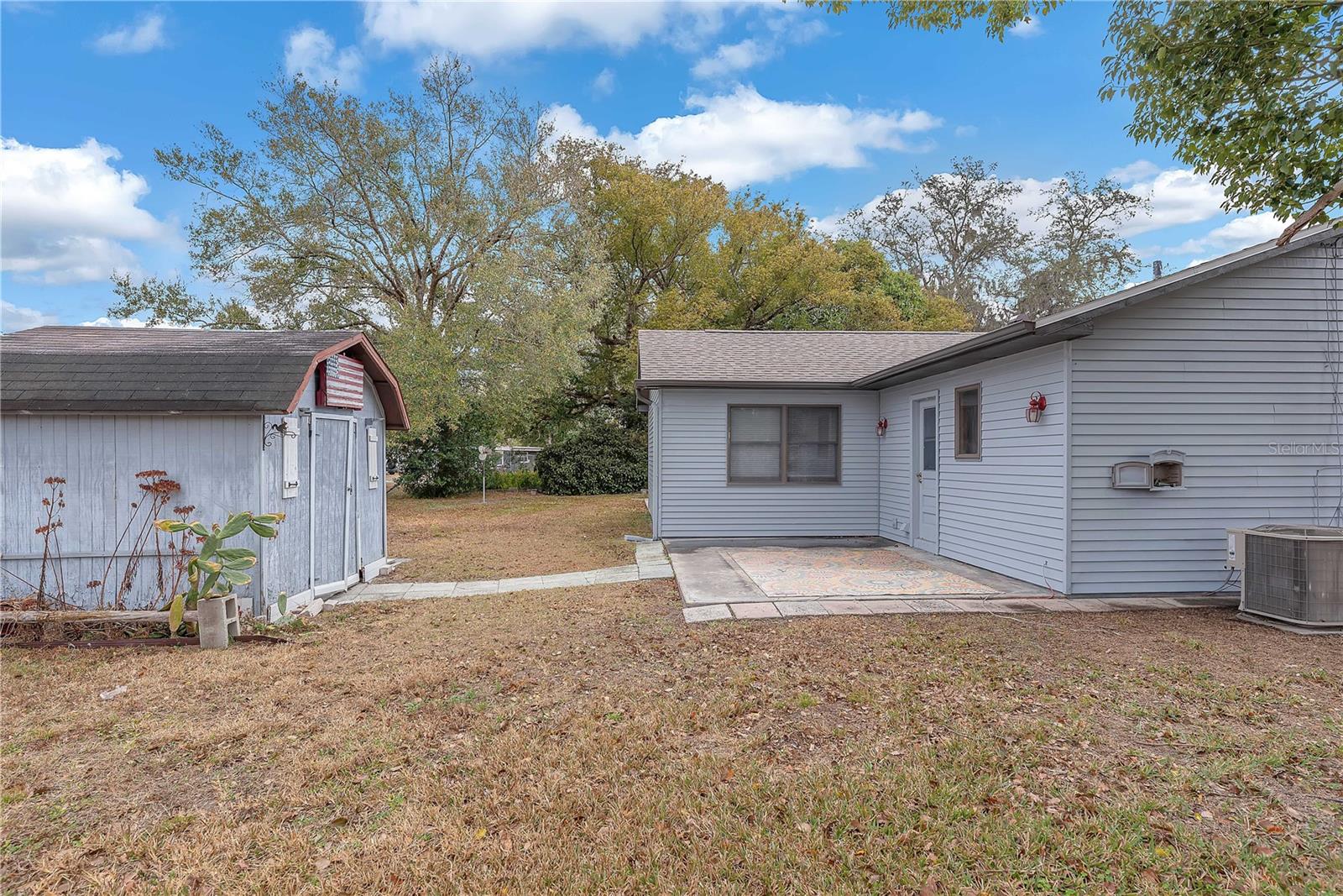 View of patio and shed and access door to the 1-car garage.