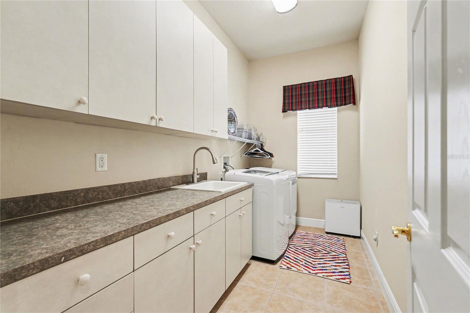Interior laundry room with sink and storage