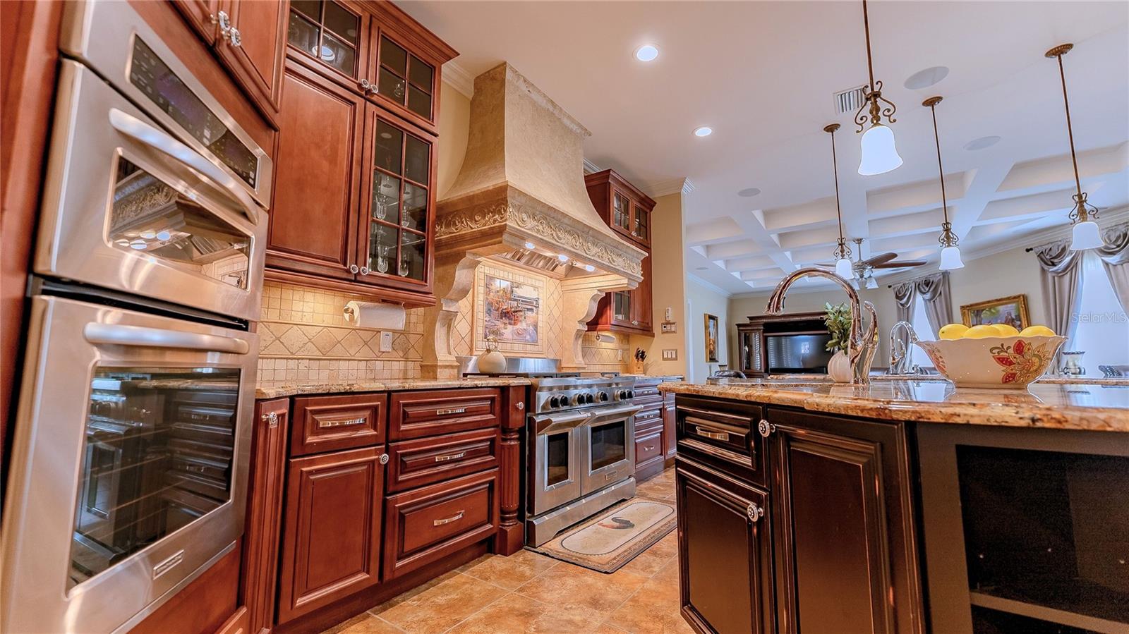 Spacious gourmet kitchen with oversized island, granite countertops, custom cabinetry, and high-end stainless appliances.