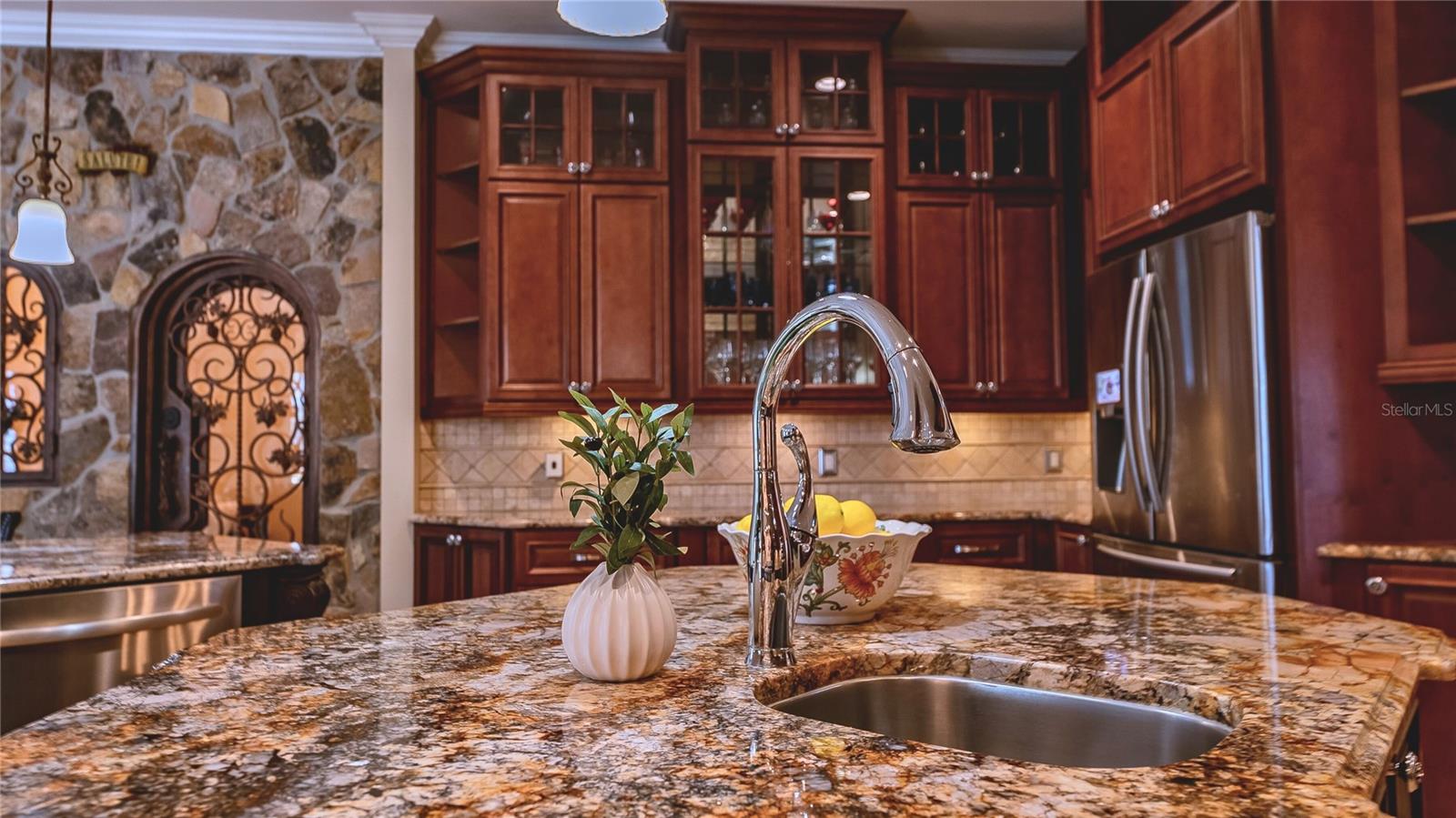 Granite-topped island with prep sink, custom wood cabinetry, and striking stone accents—designed for both everyday living and elegant entertaining.