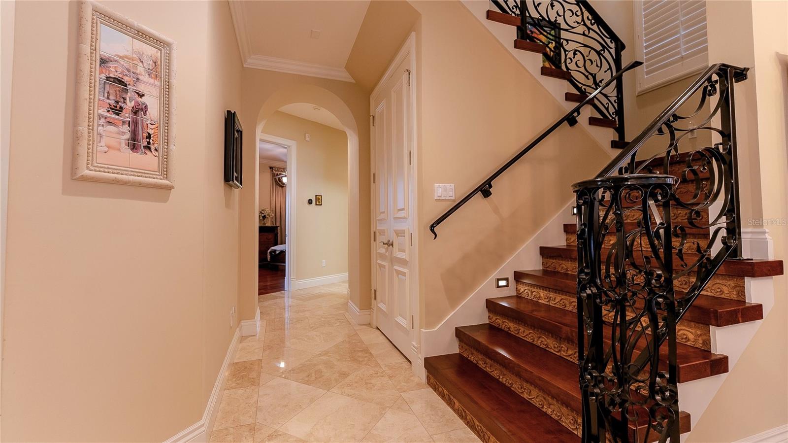 Elegant staircase with custom wrought-iron railing, wood treads, and stone-accented entry creating a grand first impression.