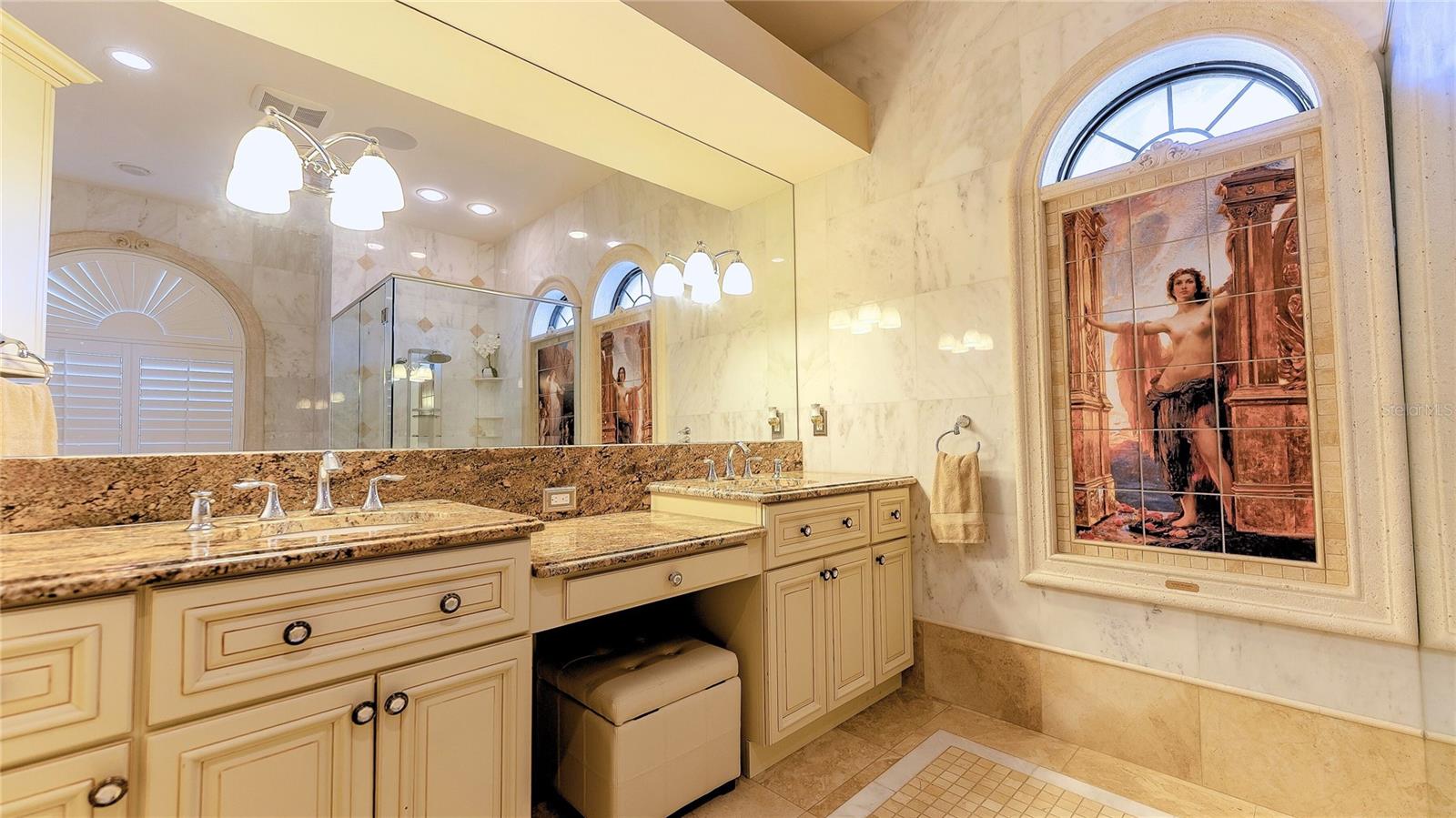 Spa-inspired primary bath with dual vanities, soaking tub, and walk-in shower framed by elegant architectural details.