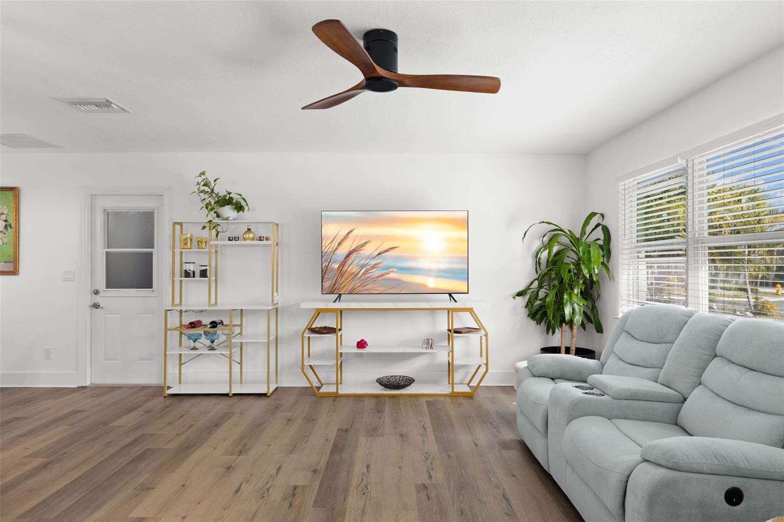 Modern ceiling fan, LVP flooring and a picture window, with a neutral color palette round out the living room.