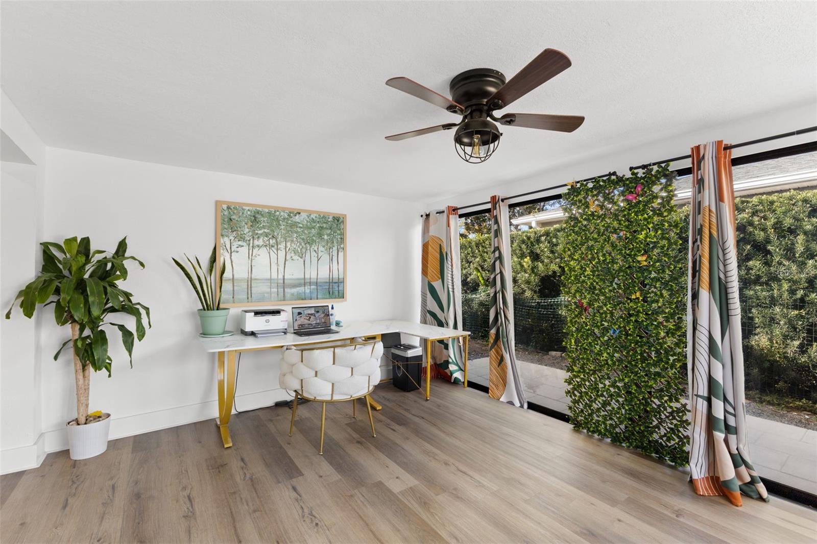 Spacious sunroom perfectly suited for a home office, art studio, or relaxation space. Oversized windows and sliding doors provide abundant natural light and direct patio access. The cohesive LVP flooring and crisp white walls create a bright, move-in-ready environment with endless possibilities.