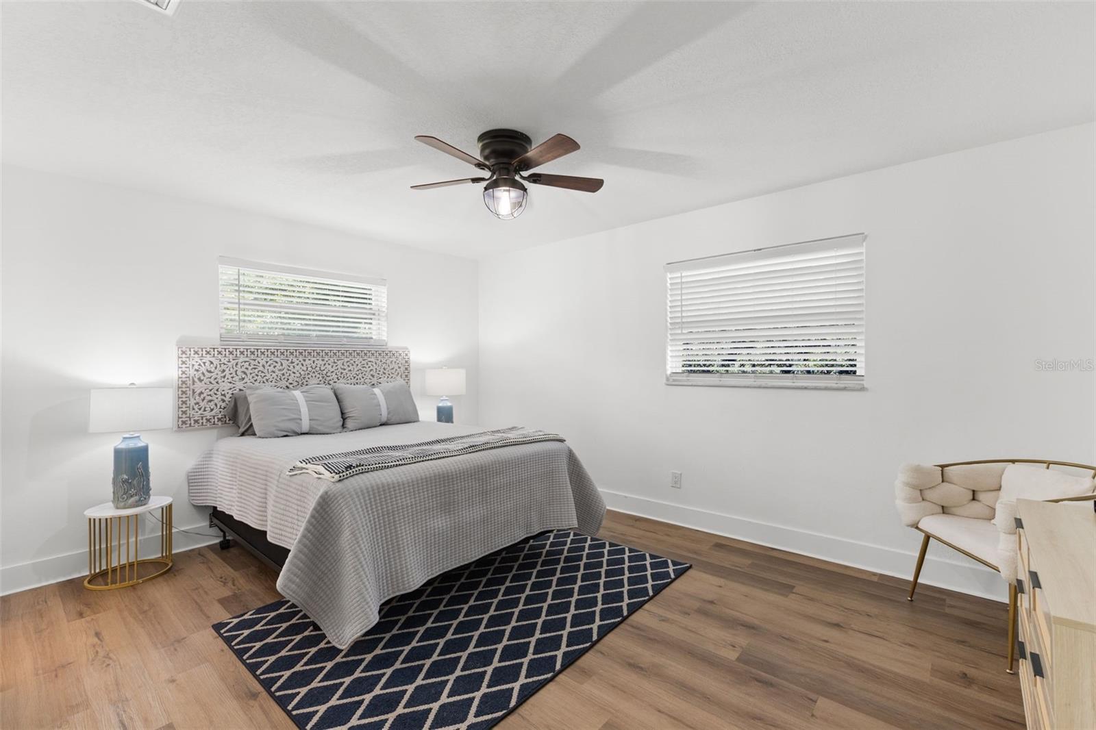 Expansive primary bedroom with wide-plank LVP flooring and ample wall space for furniture placement. Multiple windows enhance brightness while maintaining privacy. The neutral palette and updated finishes create a calm, move-in-ready environment ideal for everyday comfort.