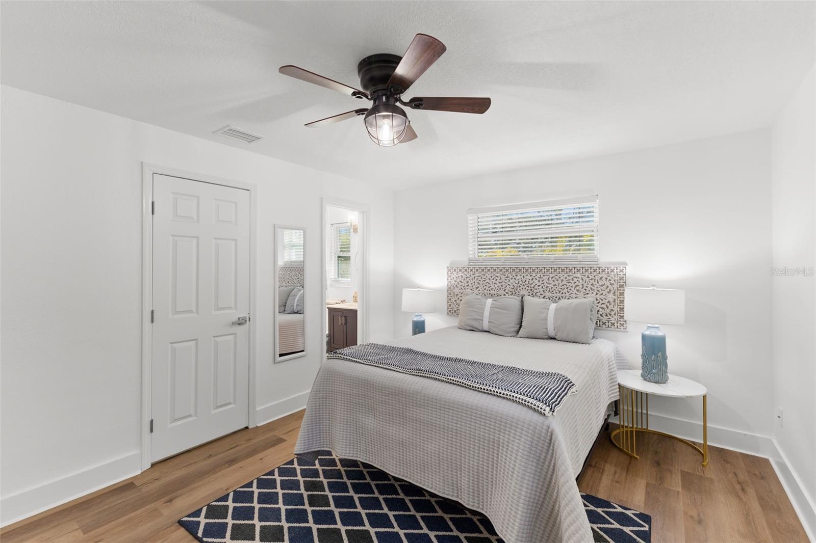 Light-filled primary suite showcasing dual windows with blinds for privacy and natural illumination. The generous layout comfortably accommodates a full bedroom set while maintaining open floor space. Coordinating LVP flooring adds warmth and continuity throughout the home.