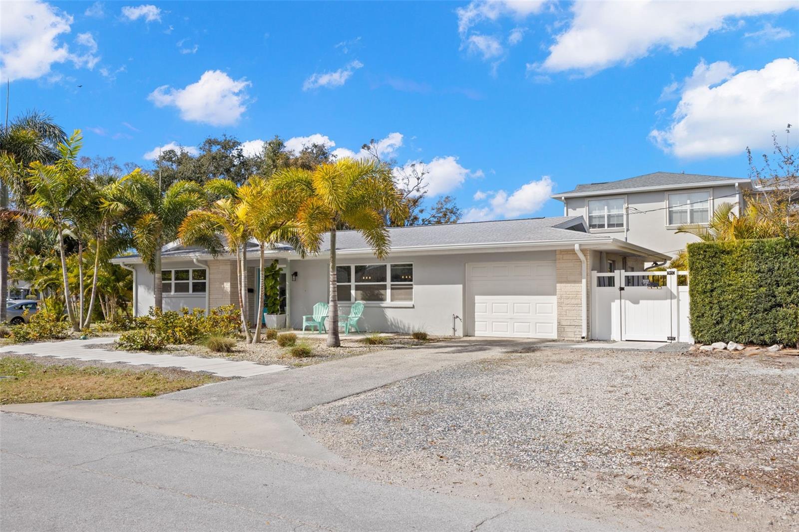 Single-story ranch style home featuring a clean, coastal-inspired façade with smooth stucco finish and contrasting stone accents. A welcoming covered front entry provides sheltered access, while multiple front-facing windows enhance curb appeal and allow for abundant natural light inside.
