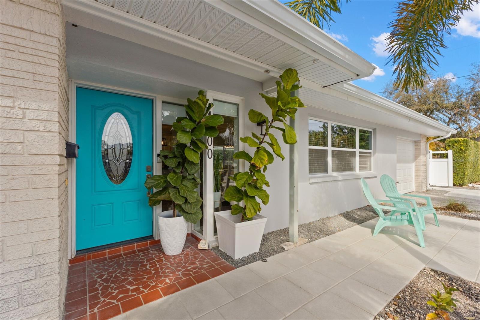 Inviting covered entry highlighted by a distinctive front door with decorative glass insert, allowing natural light into the foyer. Brick accent wall adds architectural texture, while the tiled entry threshold provides durability and visual interest. A vertical sidelight window enhances brightness at the entry.