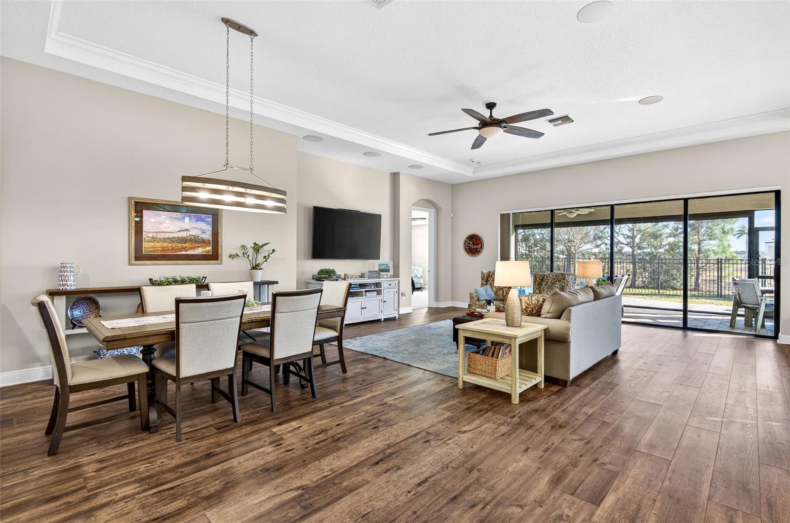 Dining/living area overlooking the backyard through triple sliding glass doors with bronze frames
