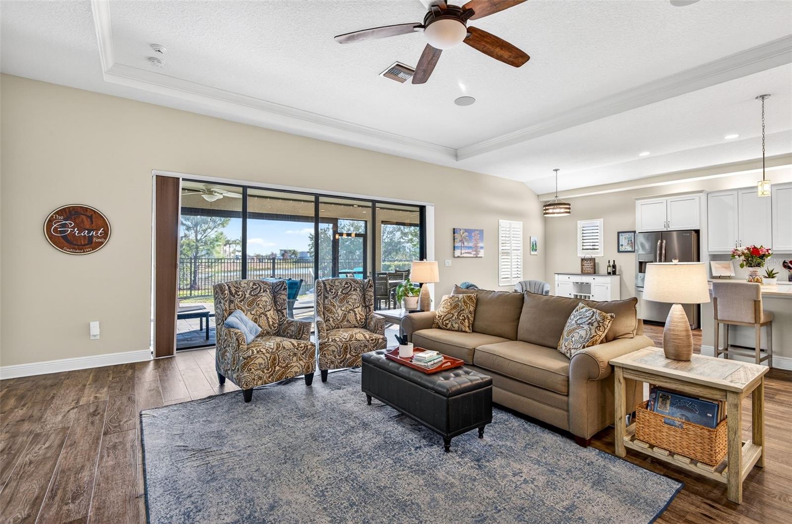 Living area with luxury vinyl plank flooring, ceiling fan, triple sliding glass doors that open up completely to the covered lanai.