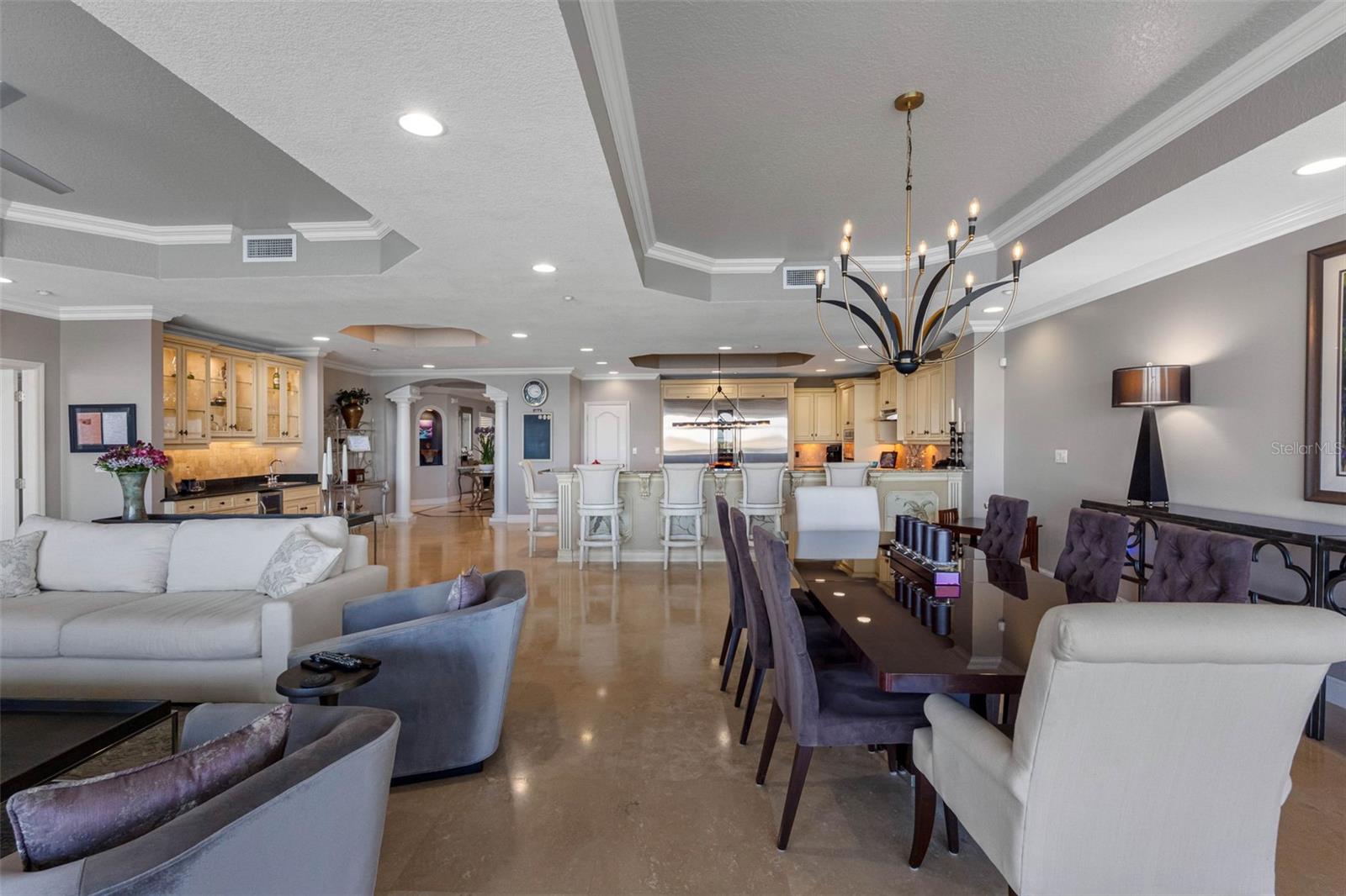 ... Great Room Toward Kitchen..  24" Travertine Marble Floors and High Tray Ceilings Through- Out Unites The Area . The Floorplan Has A Wonderful Flow To It.