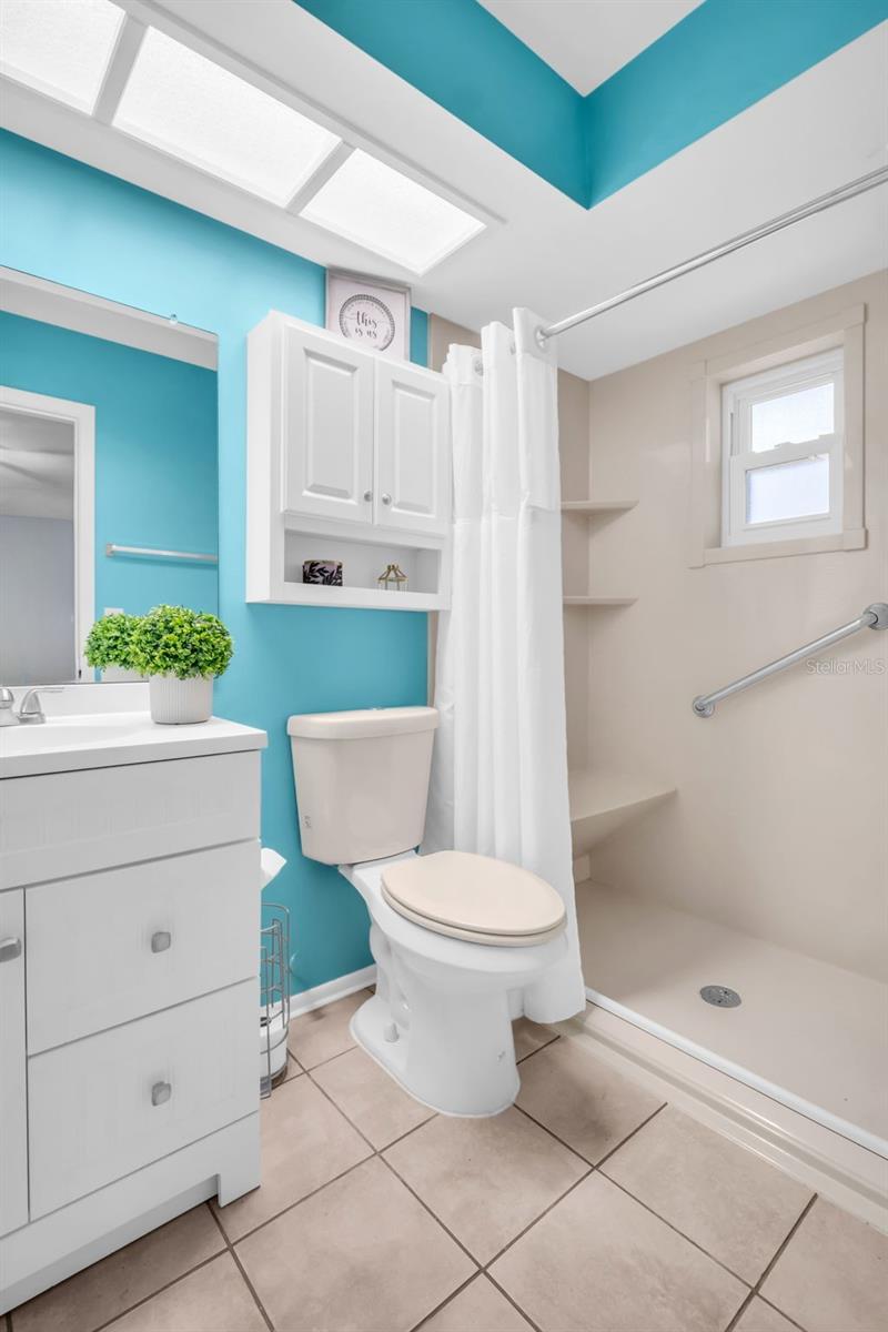 Updated en-suite featuring an updated walk-in shower with built-in shower bench, safety grab bar, and a newer vanity~