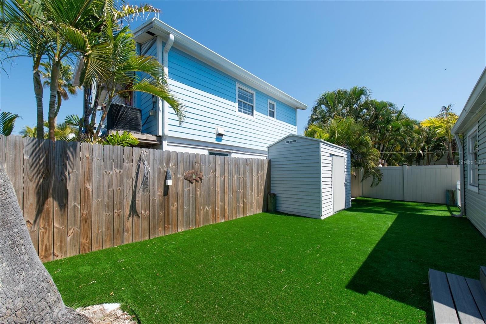 Artificial Turf in Fenced Back Yard for Low Maintenance with storage shed and wood deck.