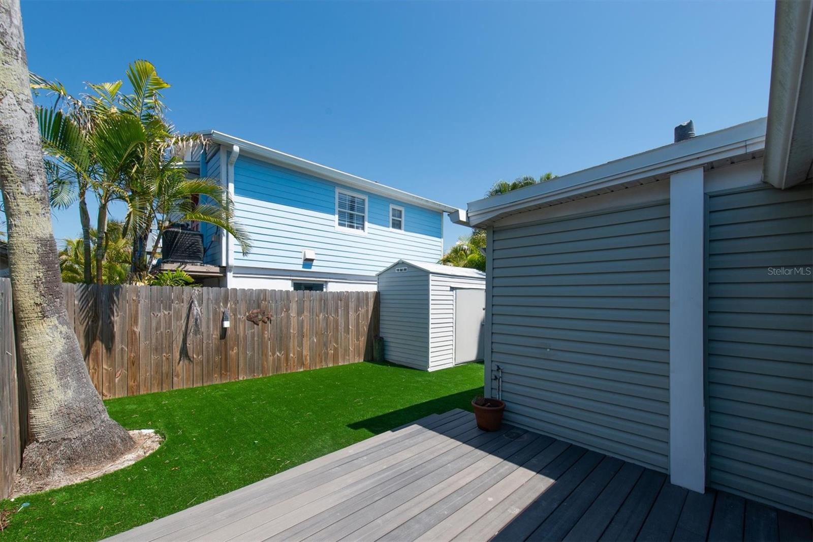 Artificial Turf in Fenced Back Yard for Low Maintenance with storage shed and wood deck.