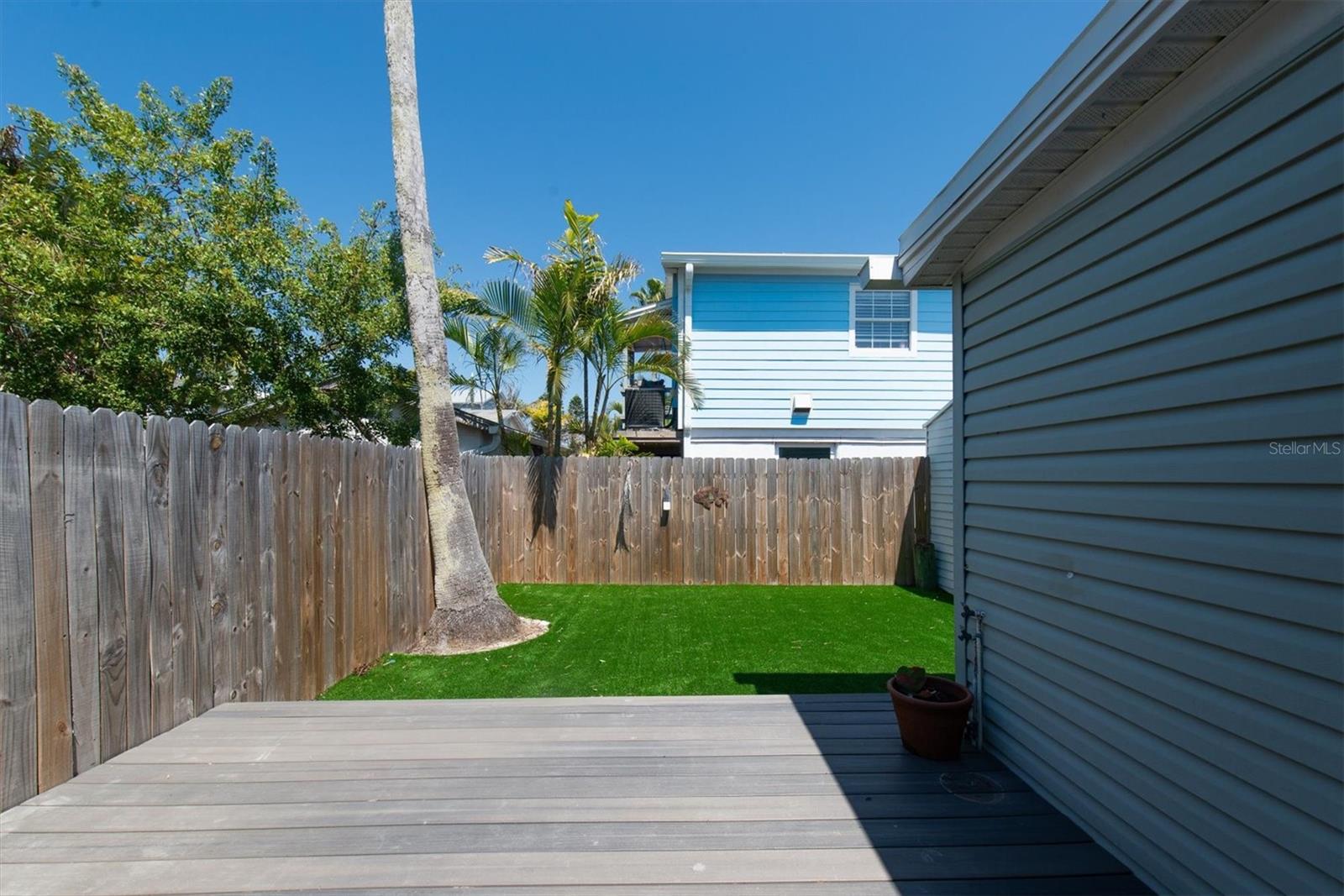 Artificial Turf in Fenced Back Yard for Low Maintenance with storage shed and wood deck.