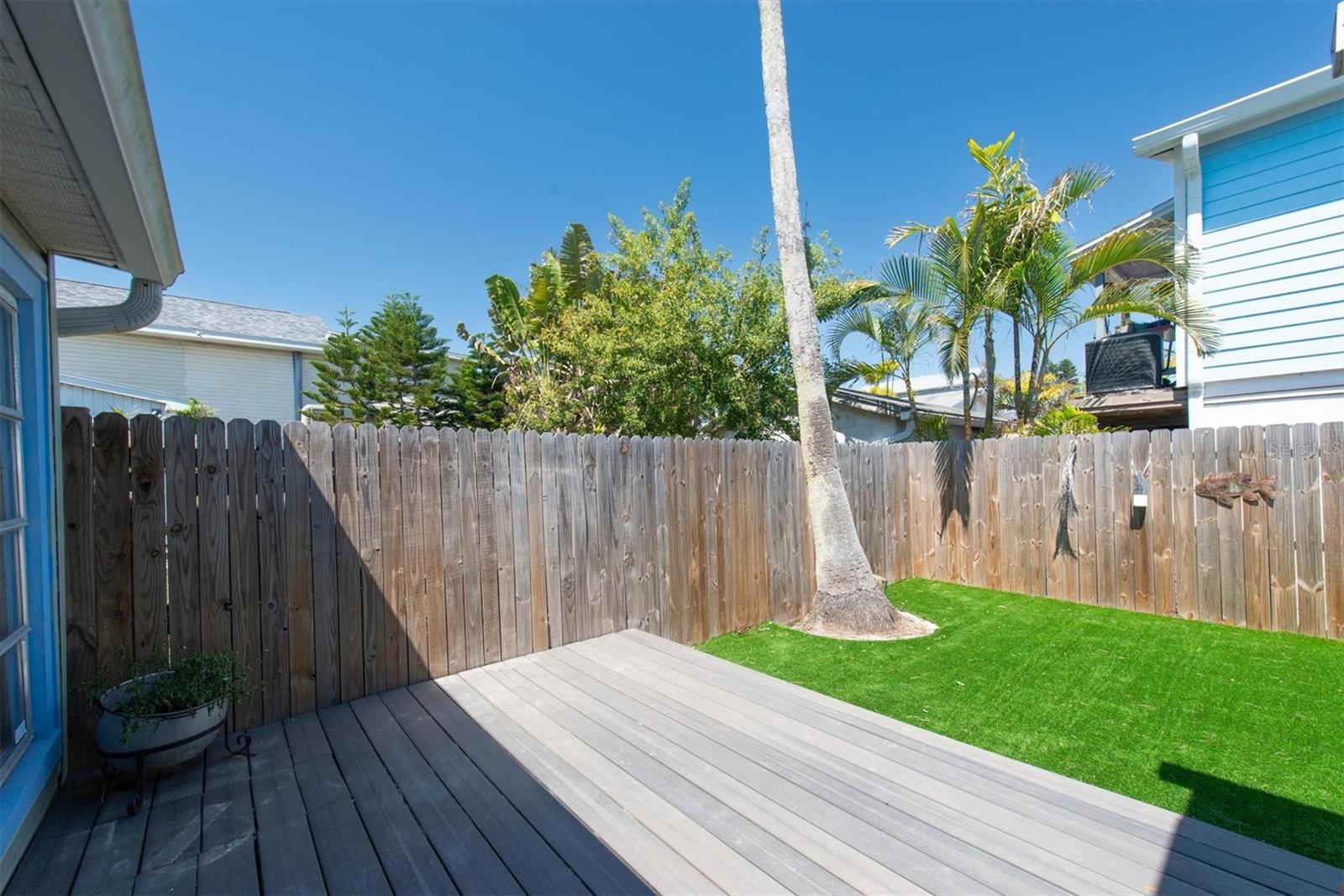 Artificial Turf in Fenced Back Yard for Low Maintenance with storage shed and wood deck.