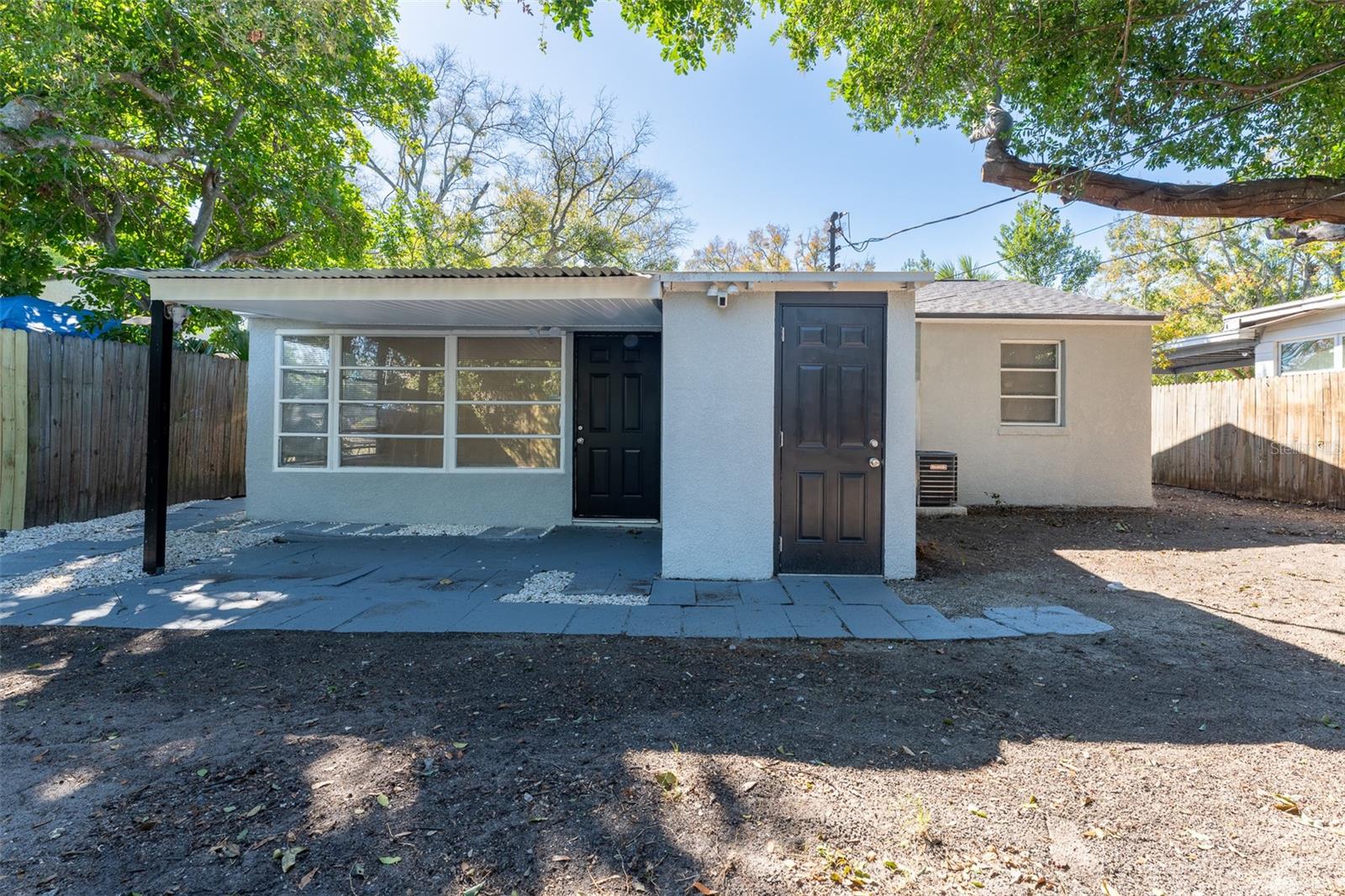 Rear exterior features a separate entrance to the utility room with washer and dryer hookups for added convenience. Enjoy a paved and covered patio area ideal for outdoor seating or entertaining, plus a spacious backyard with plenty of room to create your own outdoor retreat.