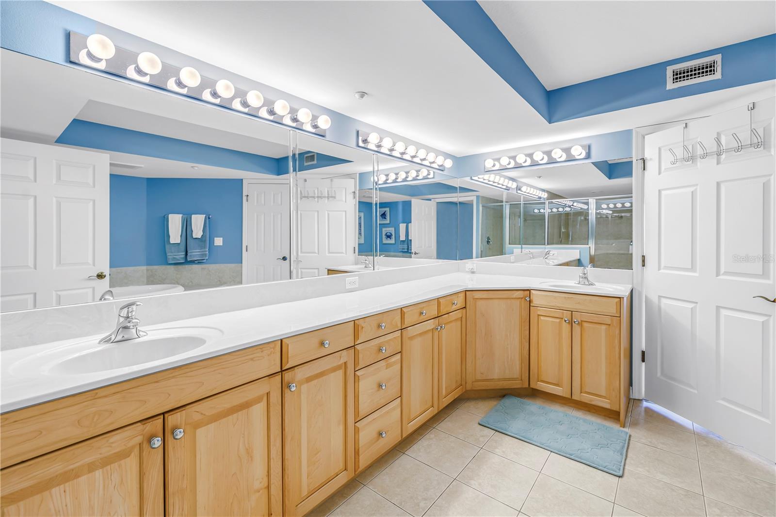 Primary bathroom linen closet, stand alone tub, water closet, standing shower, and large double vanity