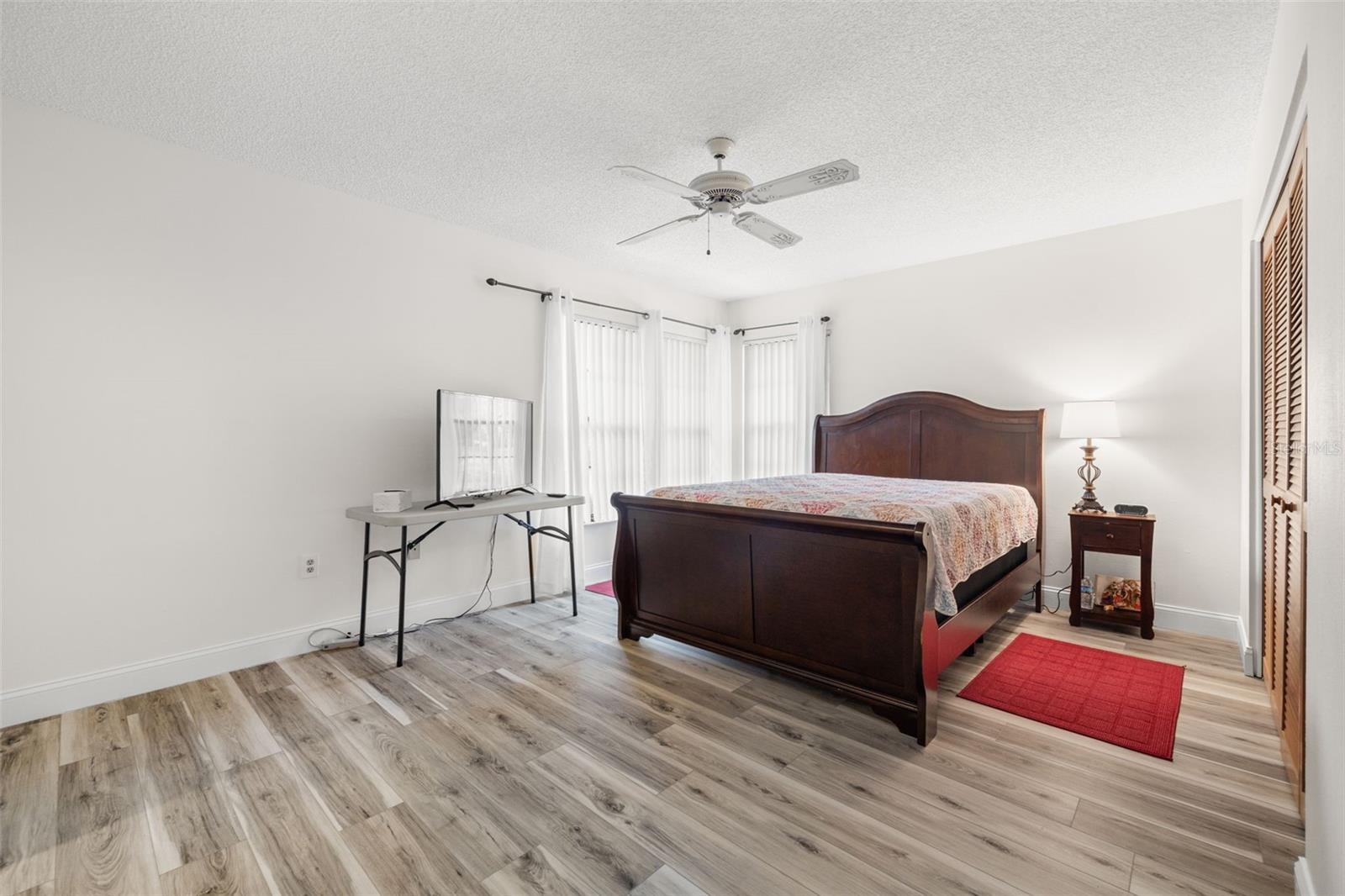 Spacious primary bedroom with newer laminate flooring, ceiling fan, large built-in closet and en-suite bathroom.