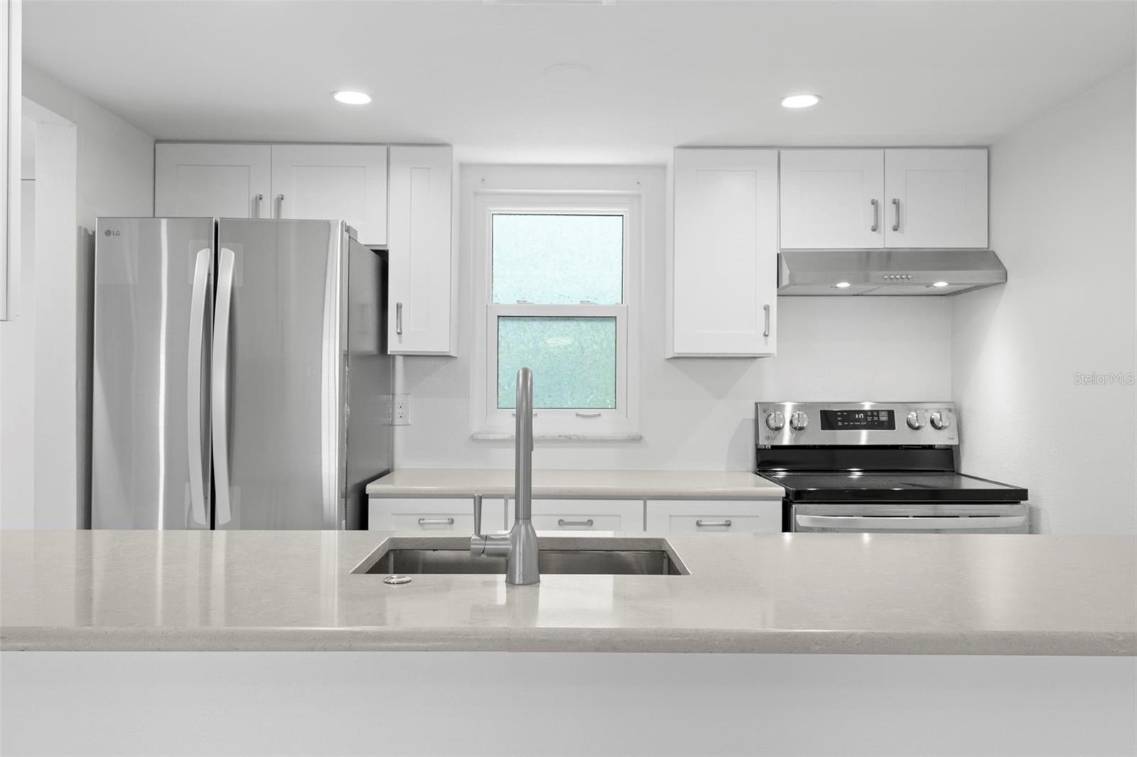 Well-appointed kitchen with generous Corian counter space, recessed lighting, stainless appliances, and open sightl ines to the dining area.