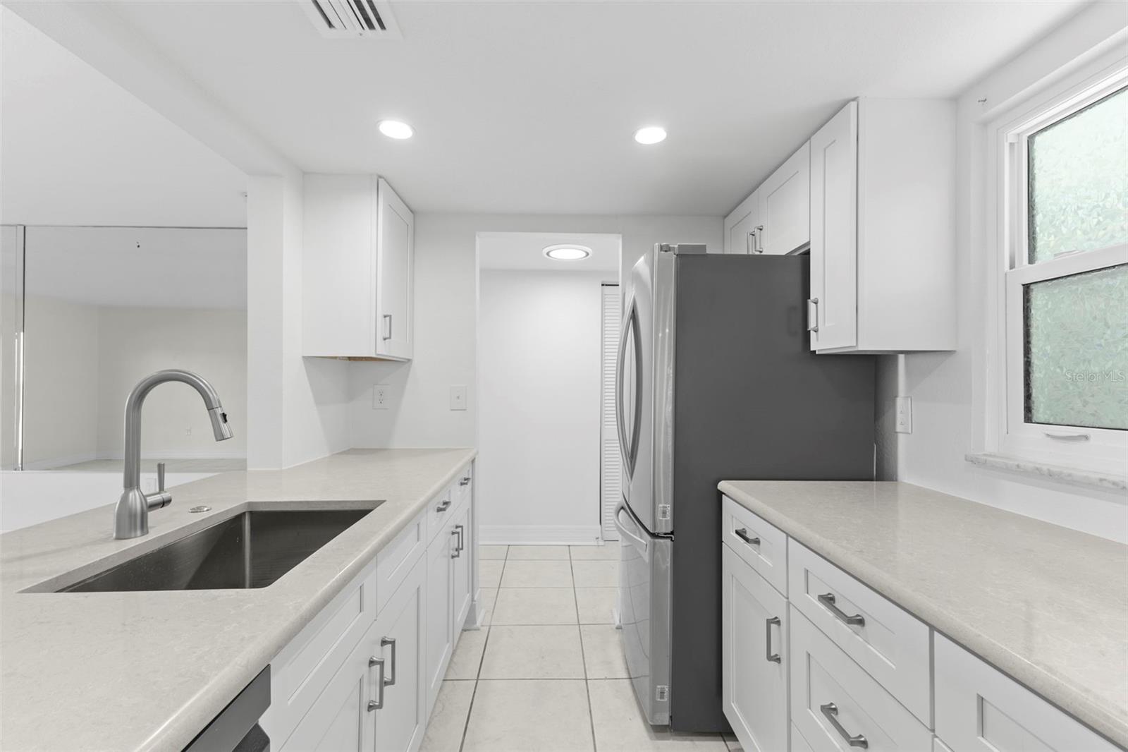 Efficient galley layout with extended prep areas, abundant cabinet storage, recessed lighting, and a sleek stainless appliances.