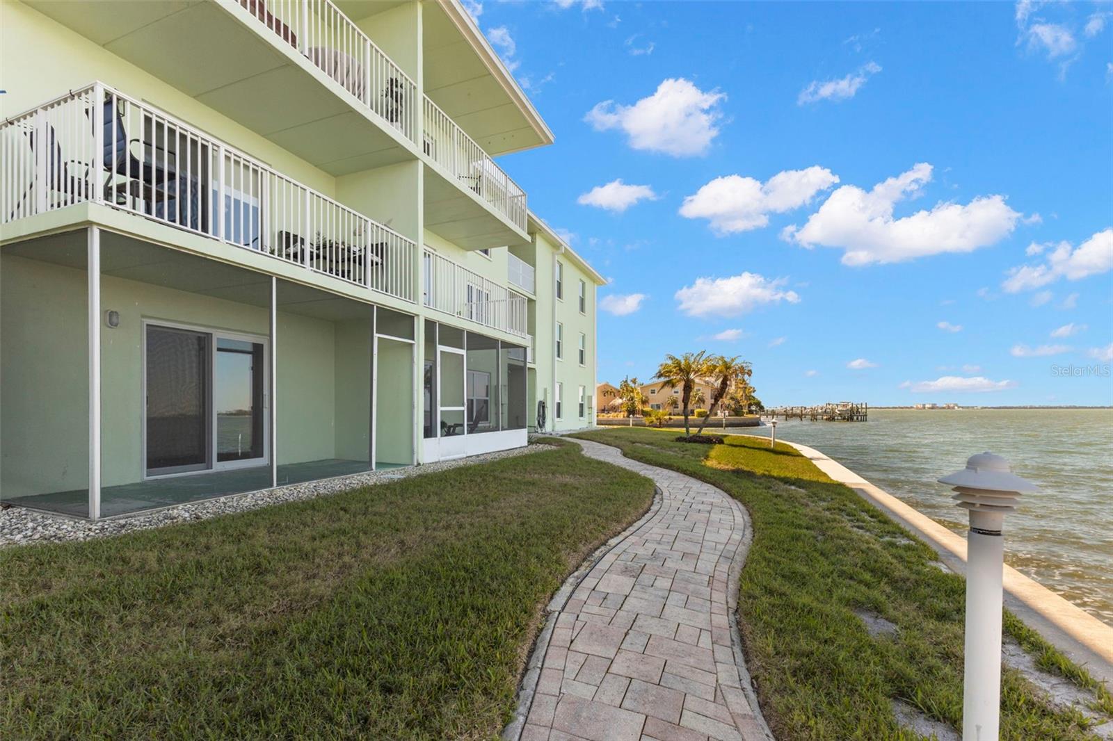 Ground-level waterfront access with a paved shoreline path, manicured grounds, and unobstructed Intracoastal views.