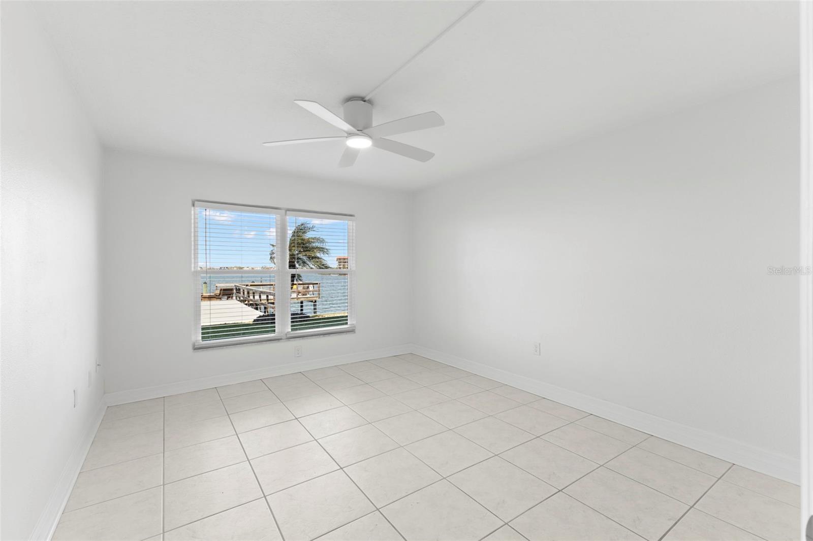 Primary bedroom featuring 18 X 18 ceramic tile flooring, ceiling fan w/remote, and waterfront views overlooking the Intracoastal and pier.