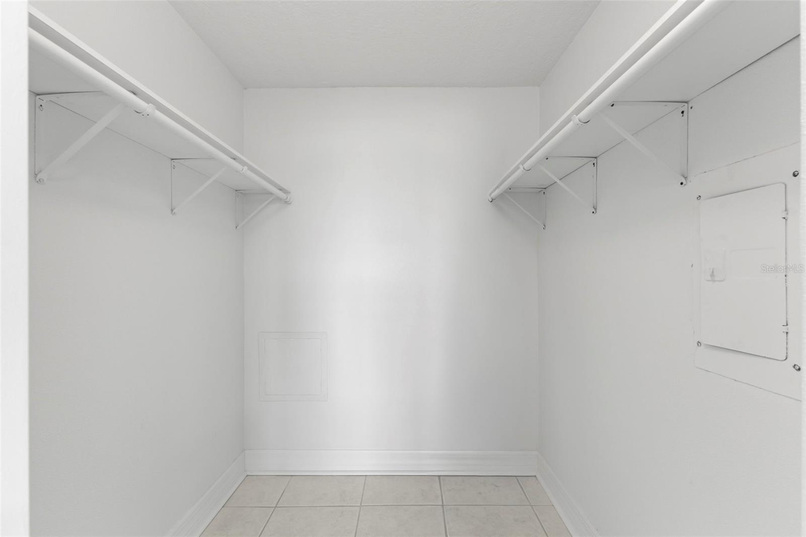 Primary walk-in closet featuring generous hanging space on both sides for organized storage.