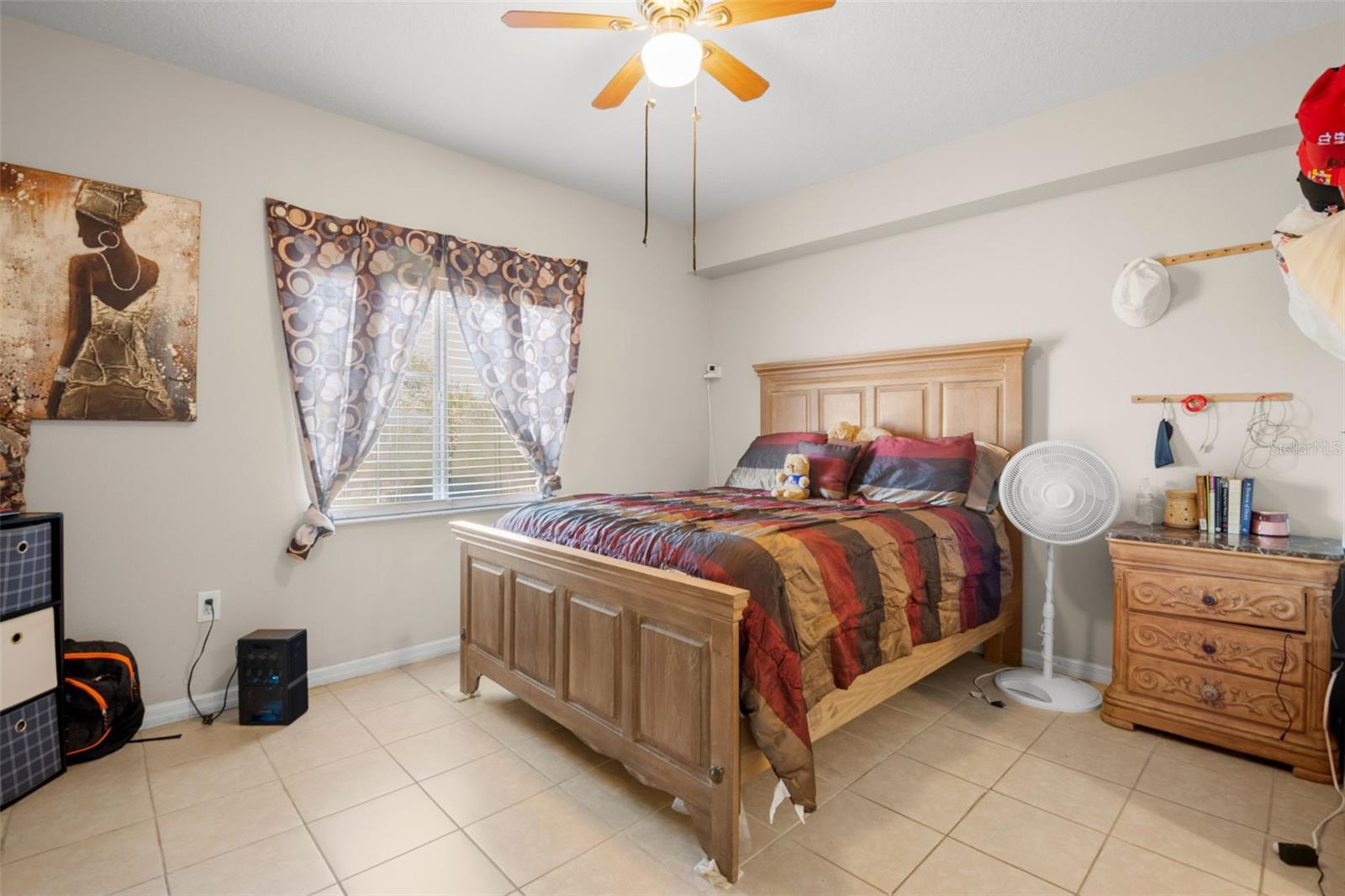 Spacious primary suite featuring ceramic tile flooring and a large window that brings in natural light. The room comfortably accommodates full-size furnishings while maintaining an open feel.