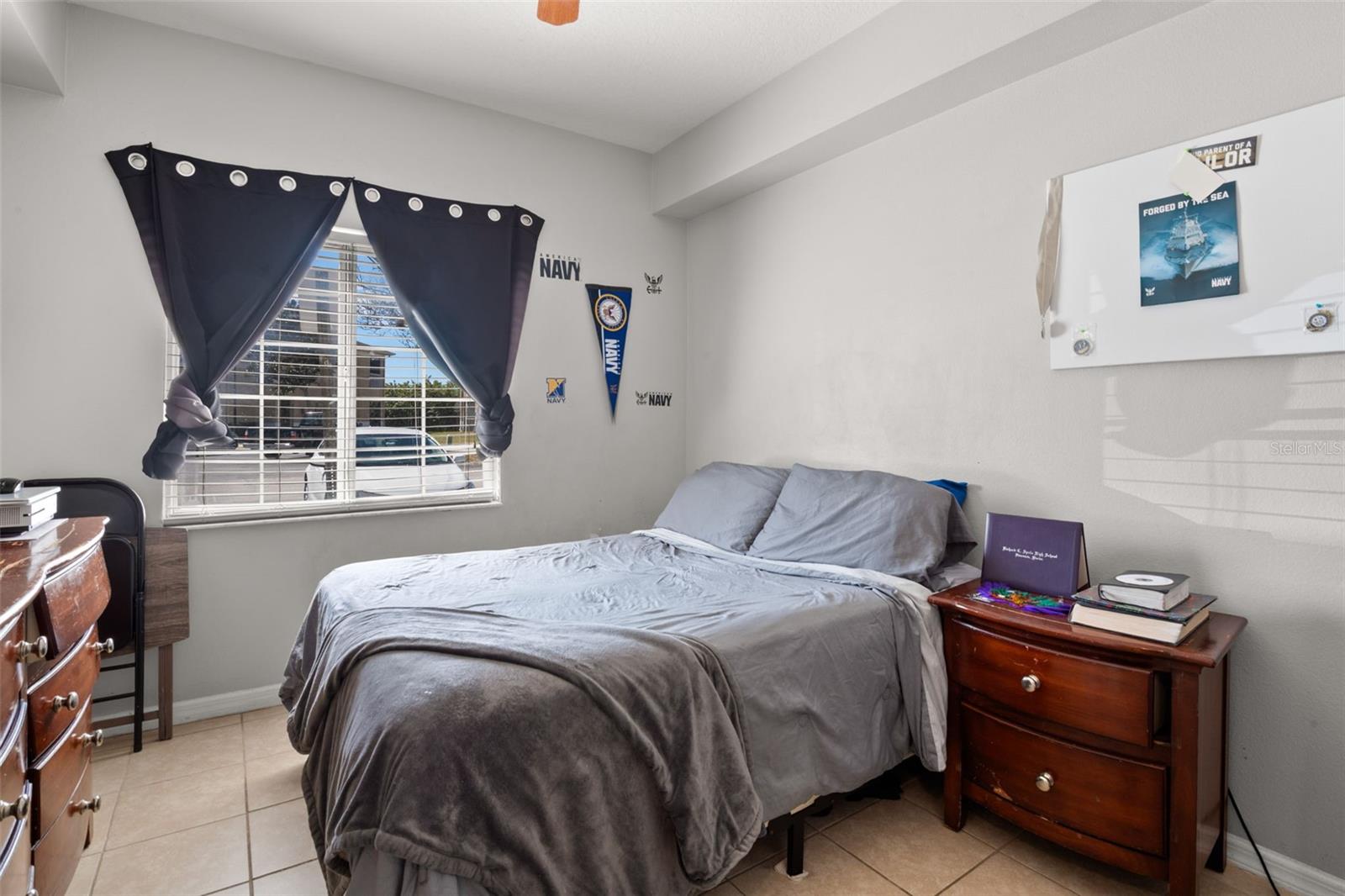 Bright secondary bedroom featuring ceramic tile flooring, a large window that fills the room with natural light, and a functional layout that easily accommodates full-size furnishings. Neutral wall tones provide flexibility for guest space, home office, or additional living needs.