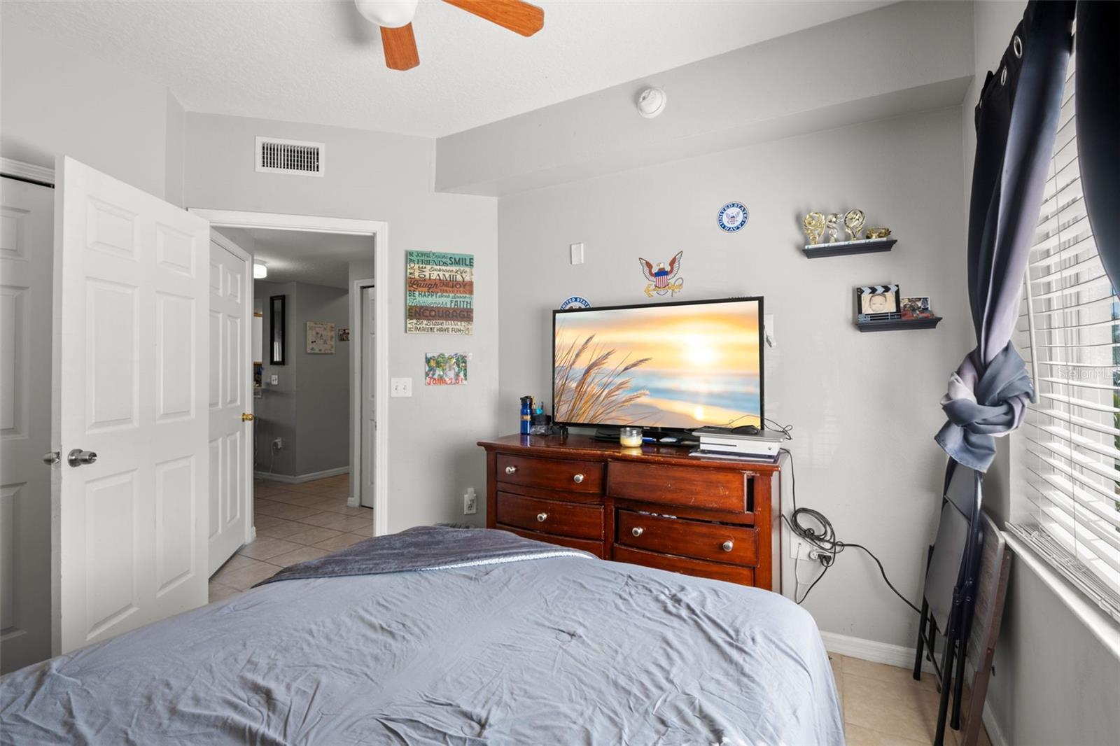 Bedroom 2 highlighting ample wall space for furniture placement and convenient access to the hallway and guest bath. The clean, neutral finishes, built in closet and ceiling fan enhance comfort within the split-bedroom floor plan.