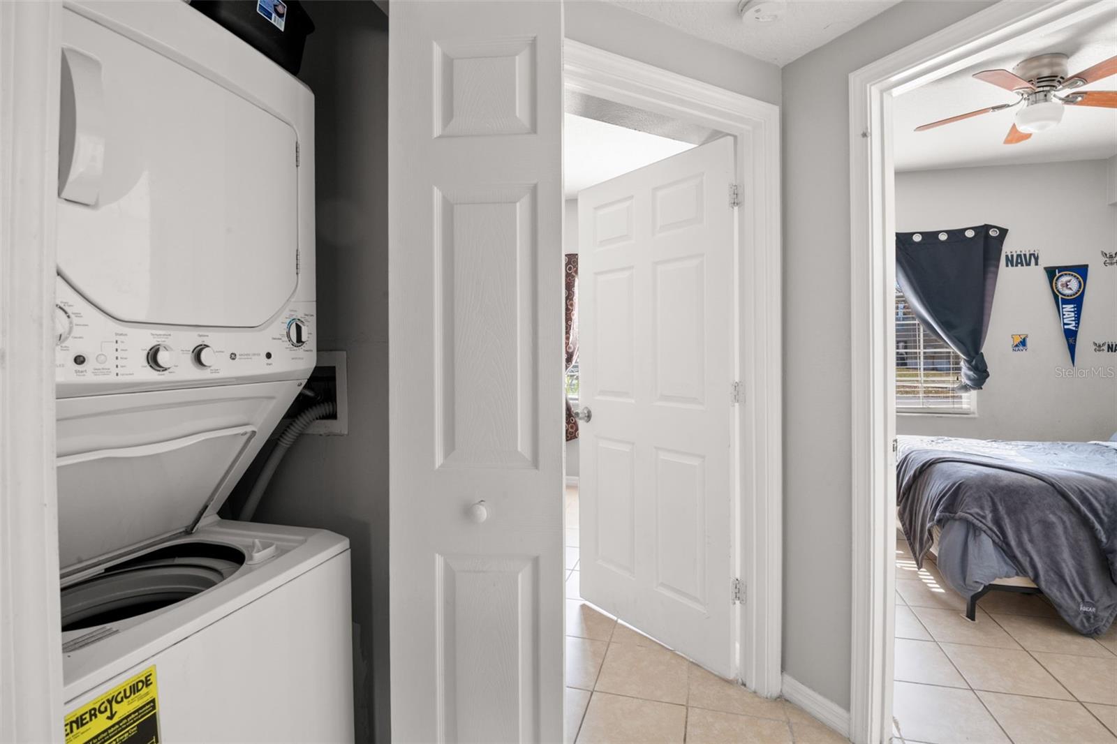Convenient interior laundry closet featuring a stacked washer and dryer, neatly tucked behind bi-fold doors for easy access. Located within the hallway for everyday functionality, offering the comfort and efficiency of in-unit laundry.