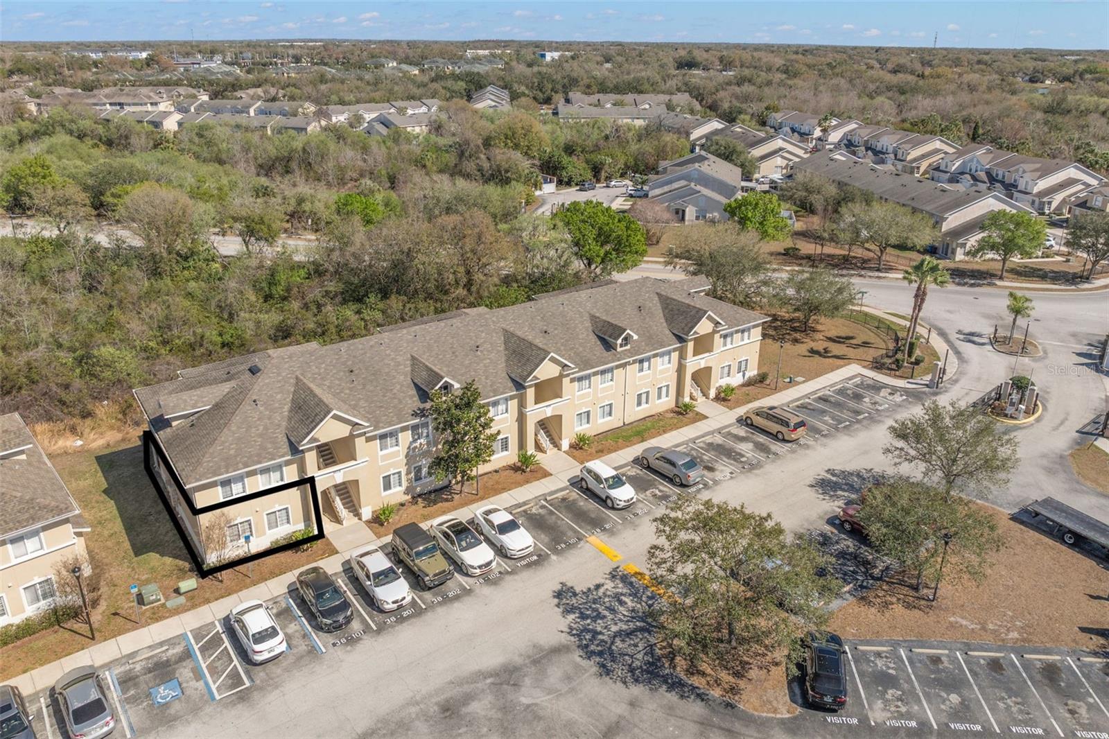 Well-maintained two-story condominium building featuring a neutral stucco exterior with architectural detailing and covered entryways. The central staircase provides access to upper residences, while ground-floor units offer convenient entry.