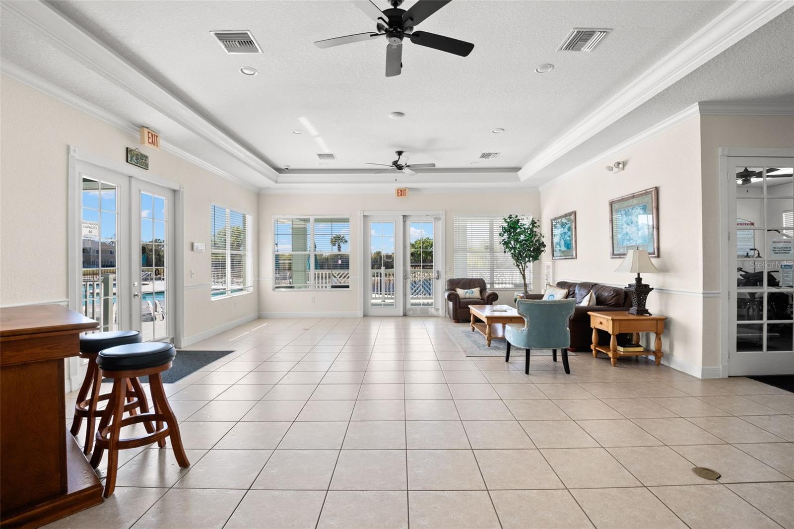 Bright clubhouse with direct access to the pool area through glass doors, offering seamless indoor-outdoor flow for entertaining or community events. The open layout provides ample space for seating and social gatherings, all within a well-maintained, thoughtfully designed setting.