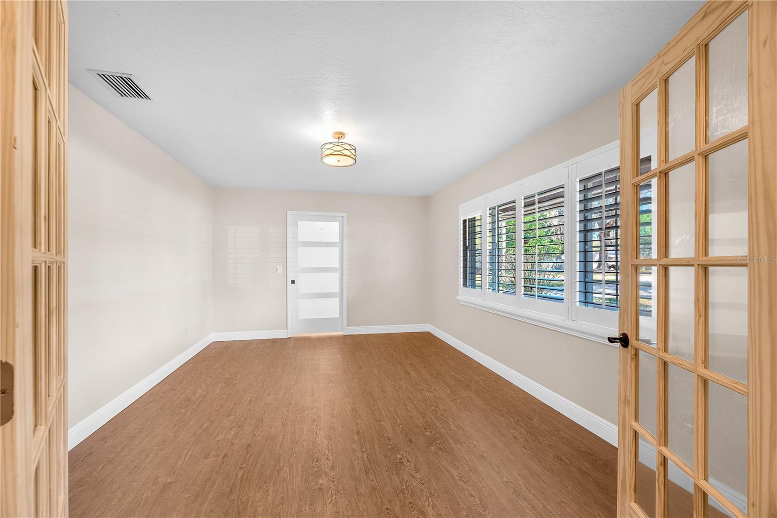 Beyond newly installed glass French doors, a versatile flex space is ideal for a home office, den, or potential fourth bedroom (no closet).