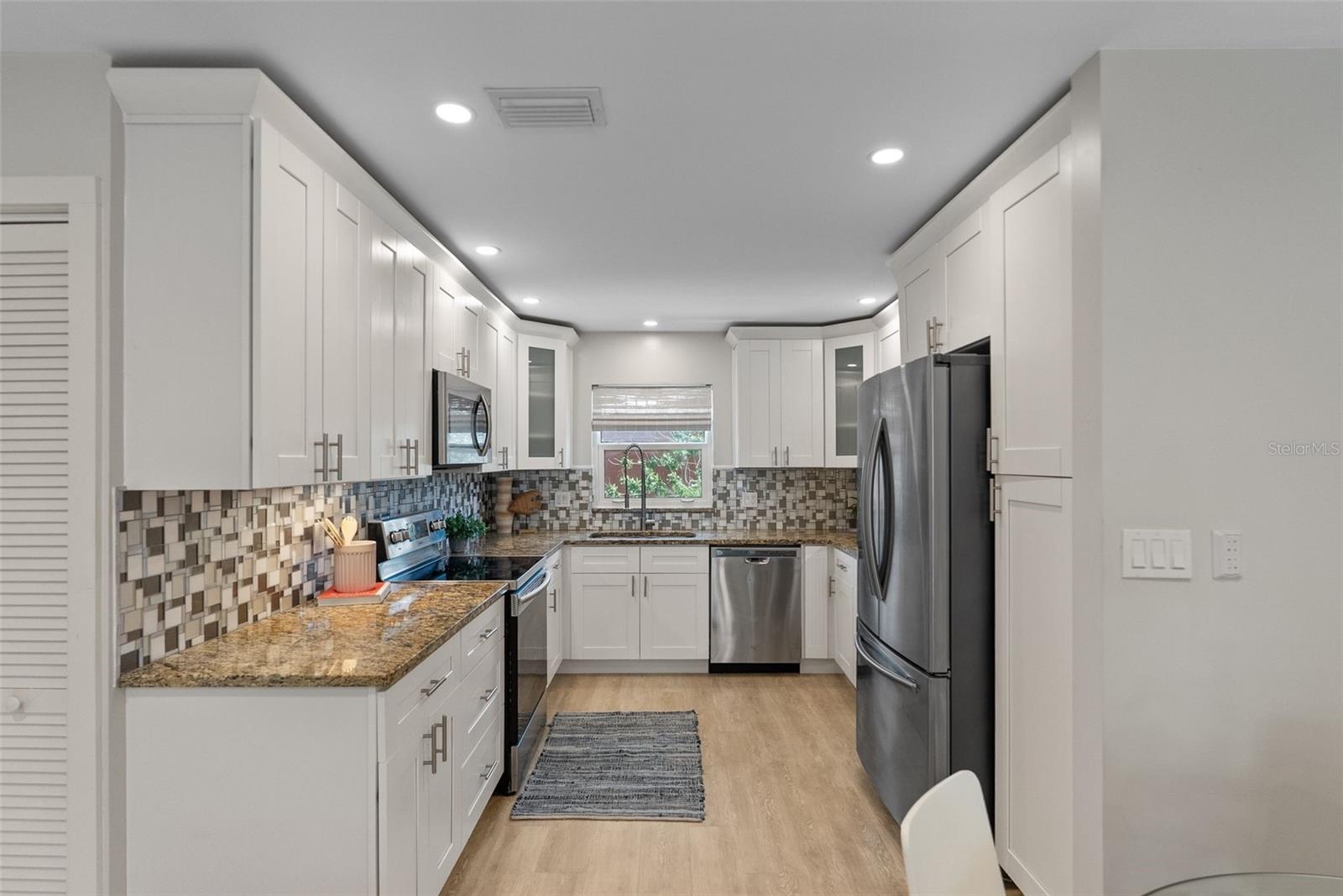 Stunning kitchen features granite counters and corner cabinets with frosted glass fronts