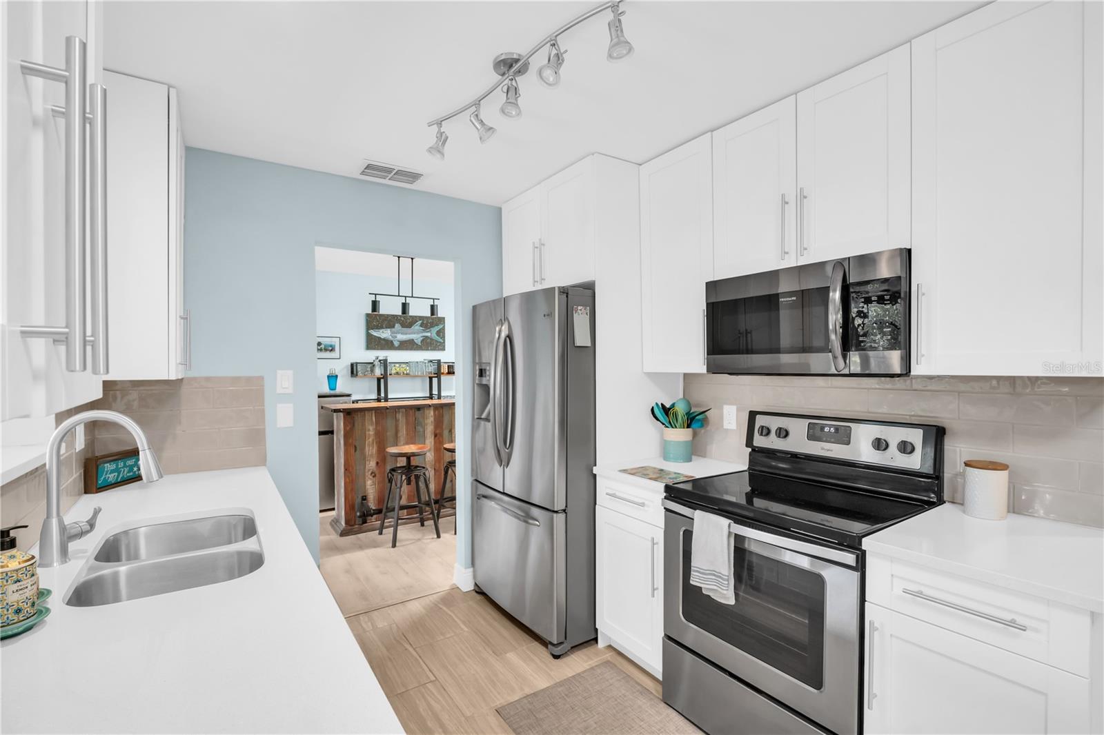 Updated white cabinets, quartz countertops, track lighting and newer appliances produce a dream kitchen ~