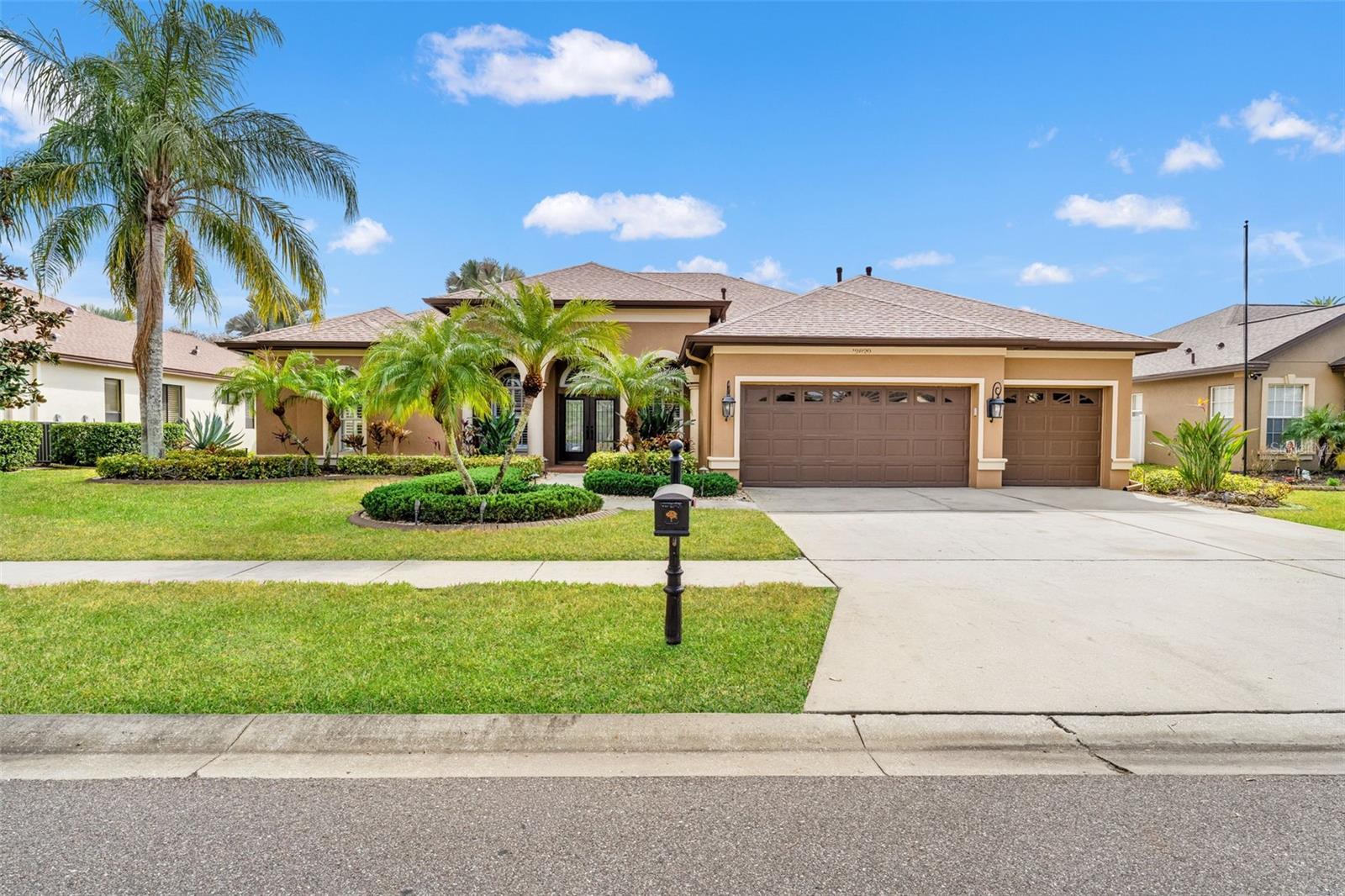This beautifully maintained home offers impressive curb appeal with manicured landscaping, palm trees, and a spacious three-car garage. A wide driveway and lush lawn create a welcoming first impression.