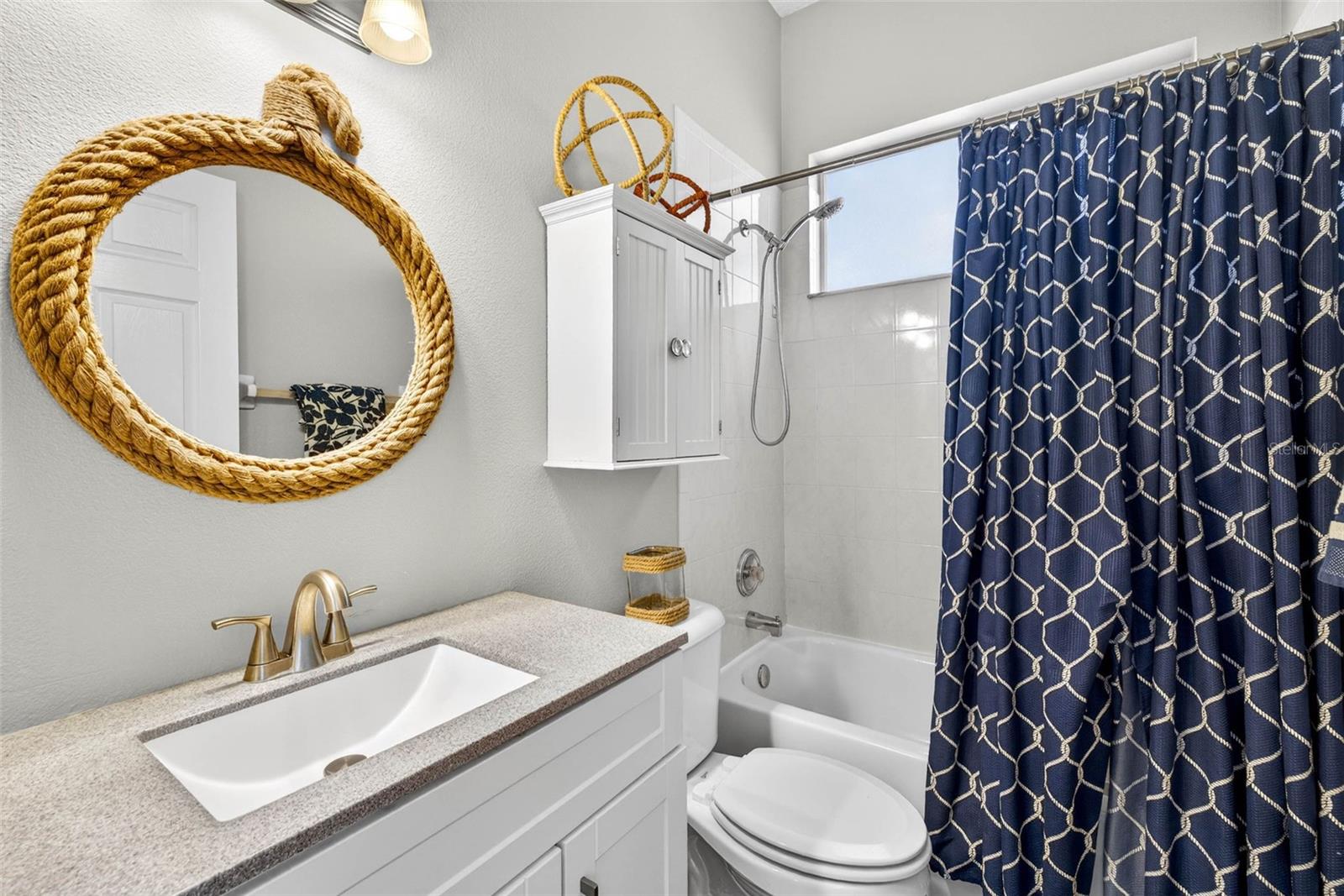 Third bathroom with comfort height vanity and handheld showerhead and window for natural lighting.